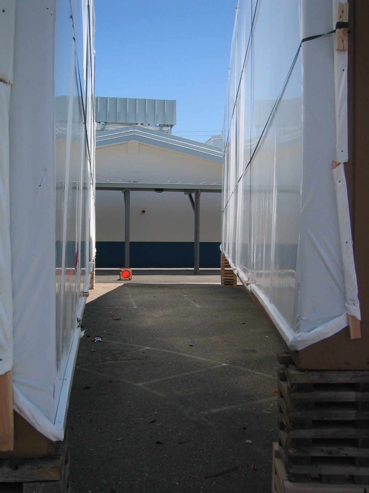 Two white portable modular classroom units side by side on a paved surface near a school building.