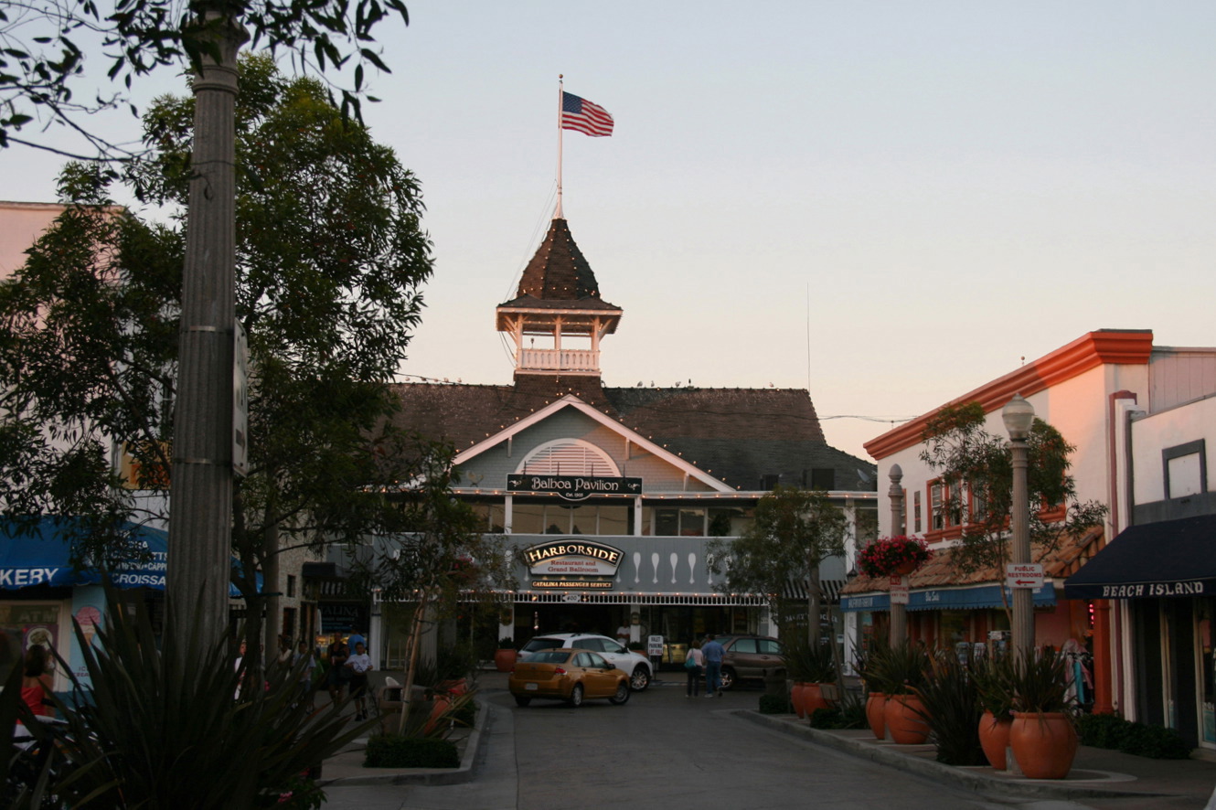 Victorian pavilion building at dusk with Harborside Restaurant sign and palm trees.