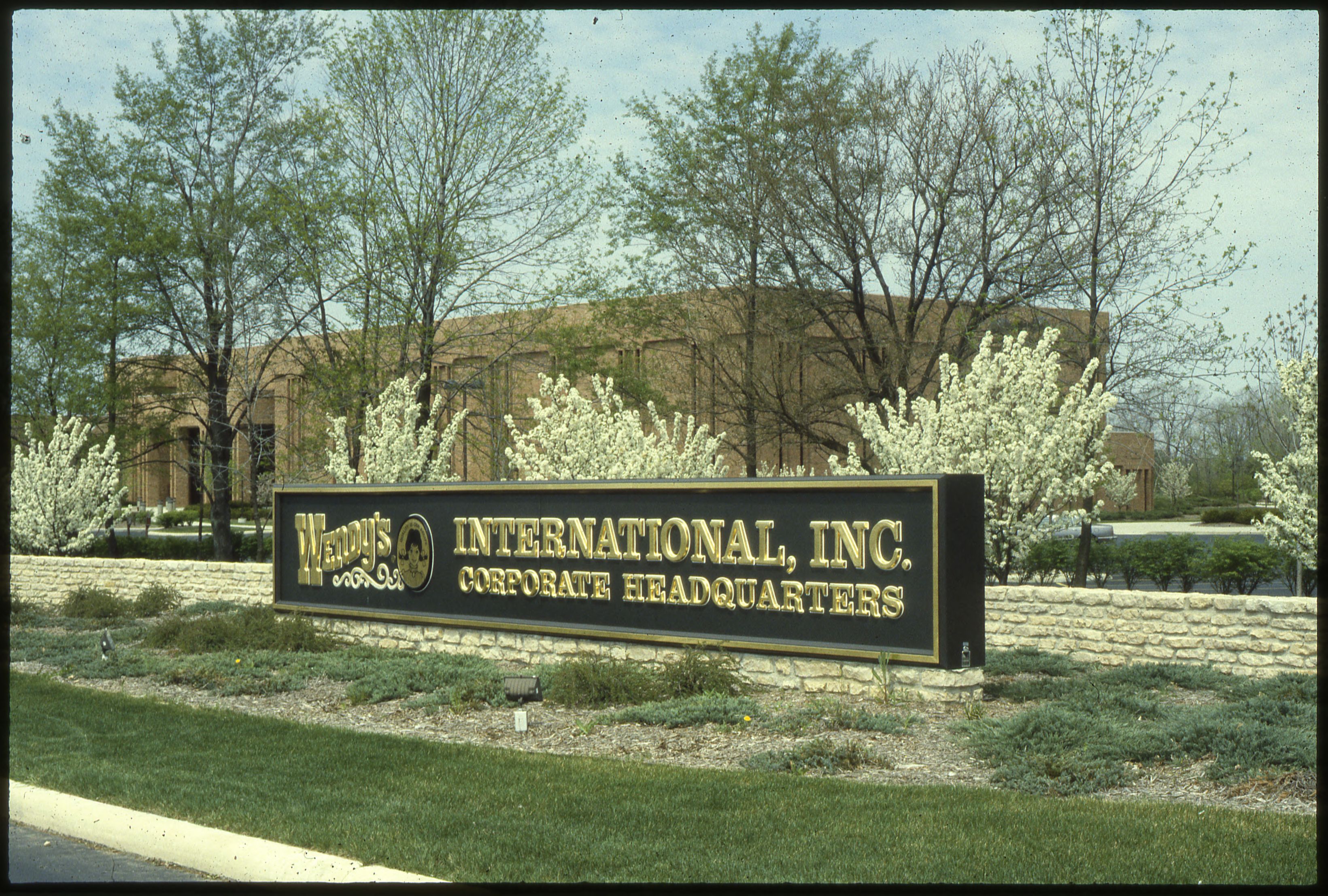 Stone monument sign reading Wendy's International Inc. Corporate Headquarters with blooming trees
