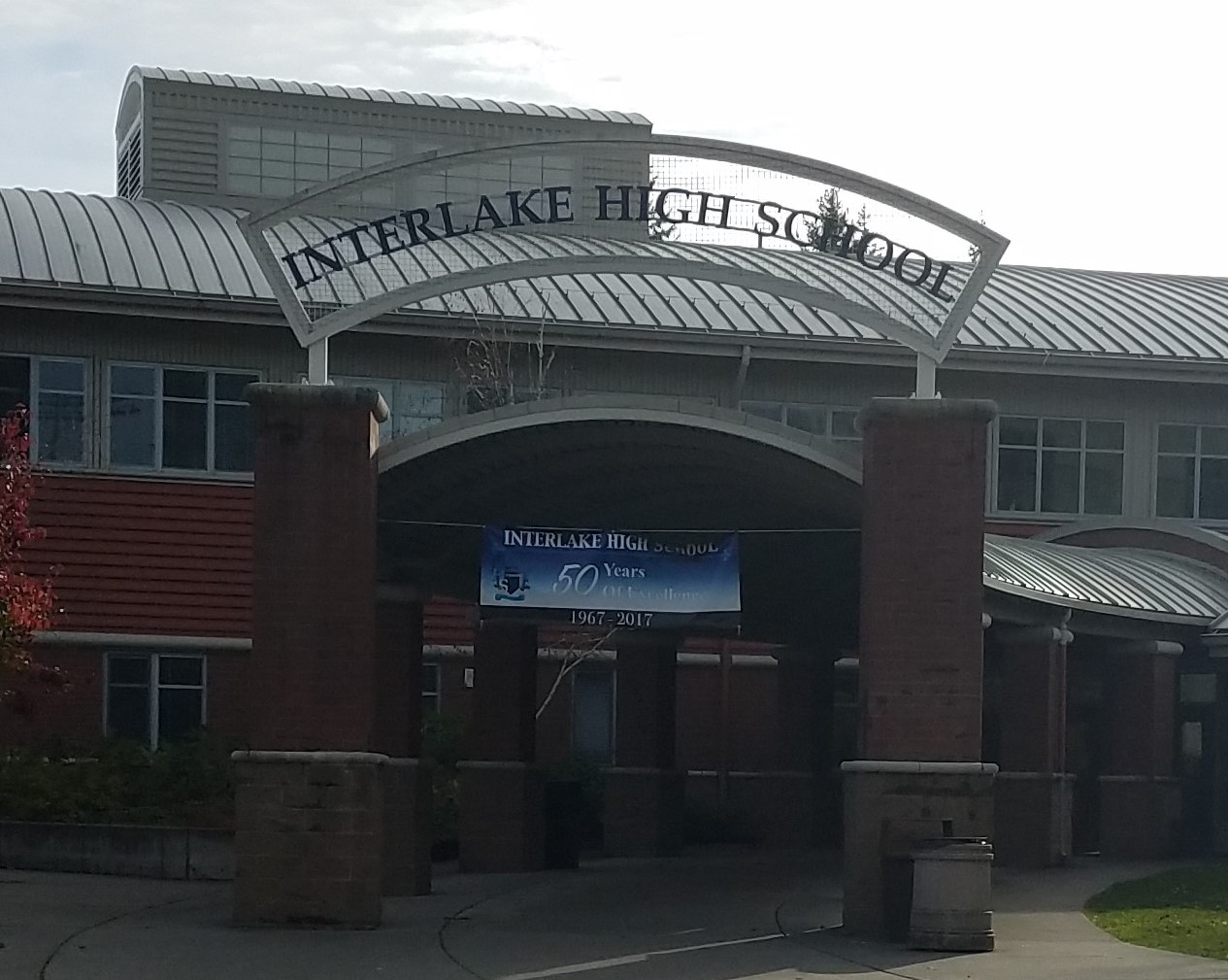 Main entrance of a brick high school building with an arched metal sign.