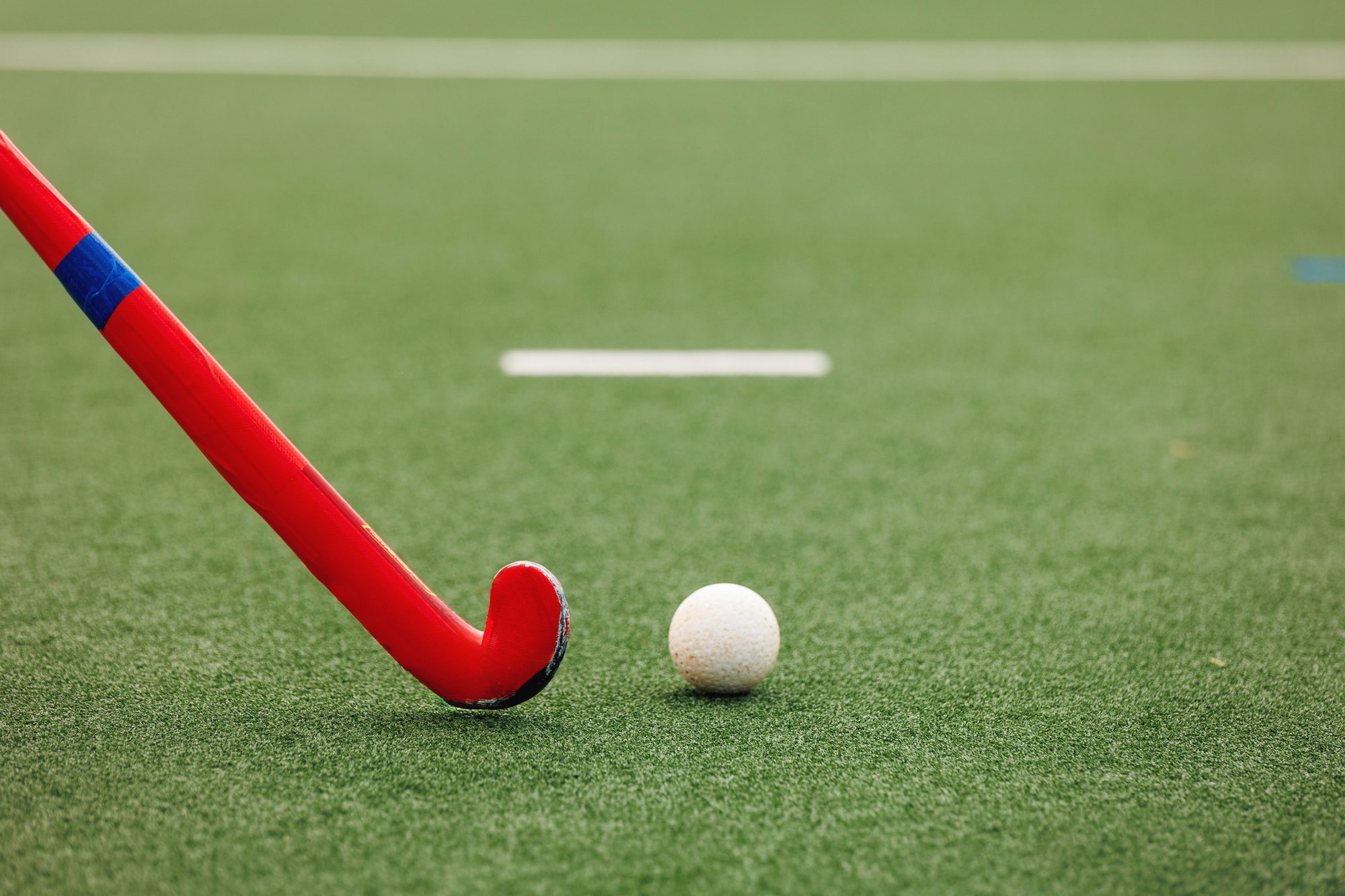 Field hockey stick and ball on artificial turf pitch