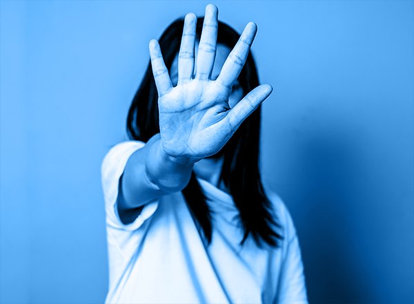Person extends open palm toward camera in a stop gesture, blue monochrome treatment.