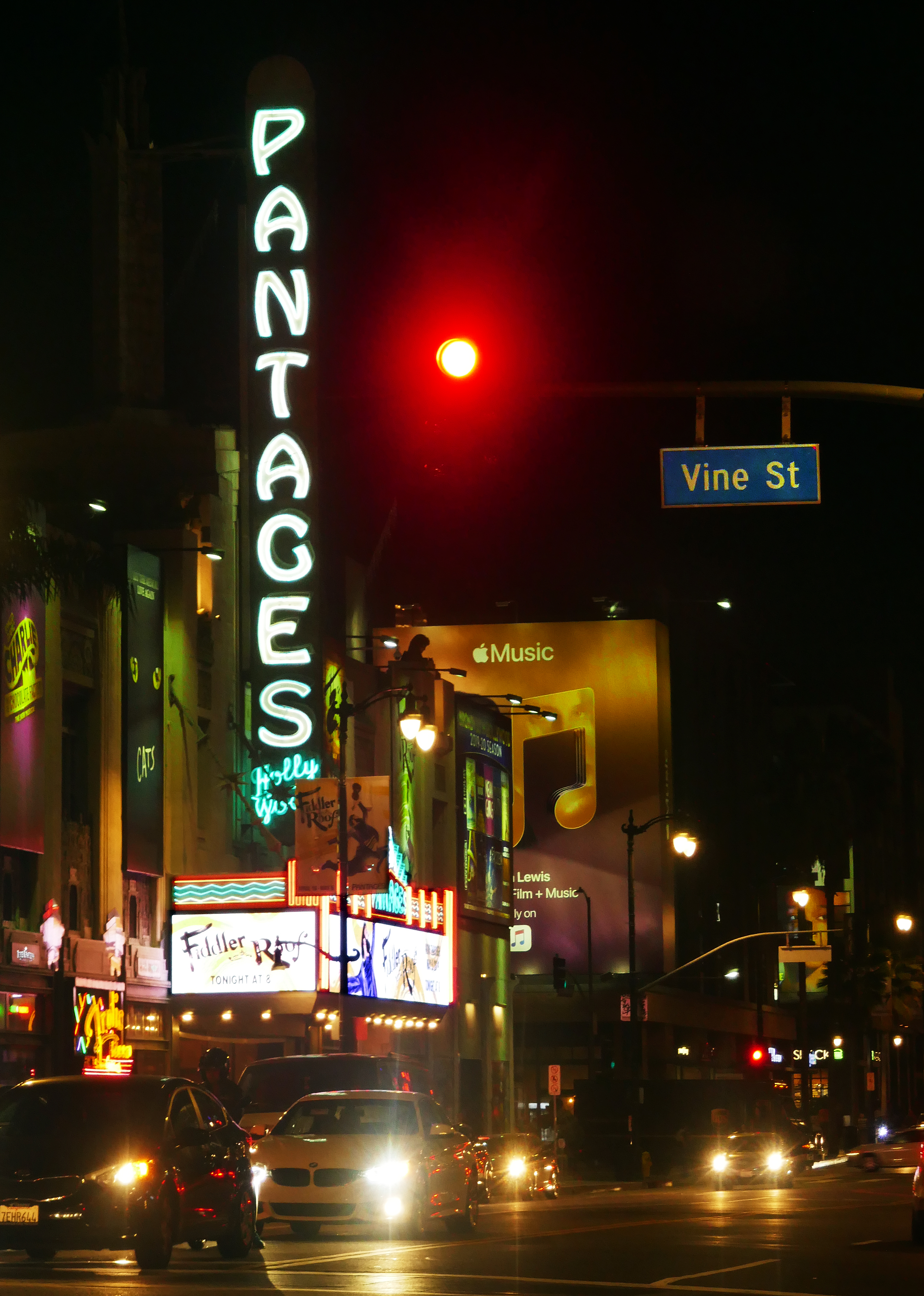 Glowing green neon Pantages marquee sign lit up at night on Hollywood Boulevard.