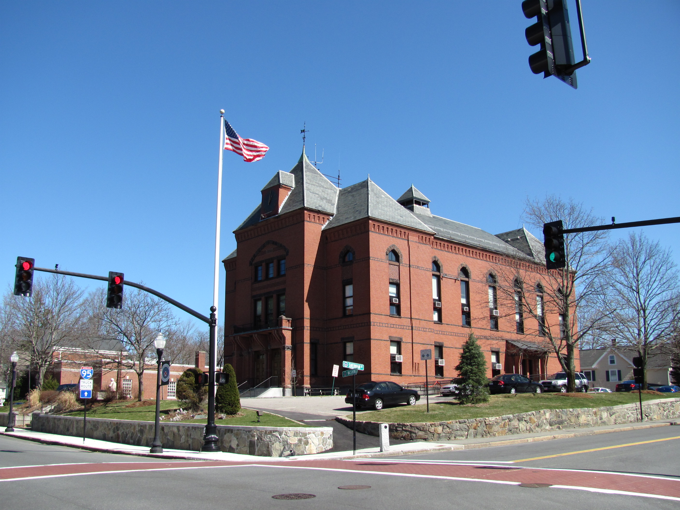 Red brick Victorian-style Canton Town Hall at a street corner with an American flag.
