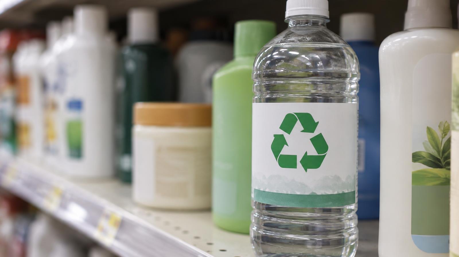 Plastic bottle with a recycling symbol on its label among other product containers on a shelf.