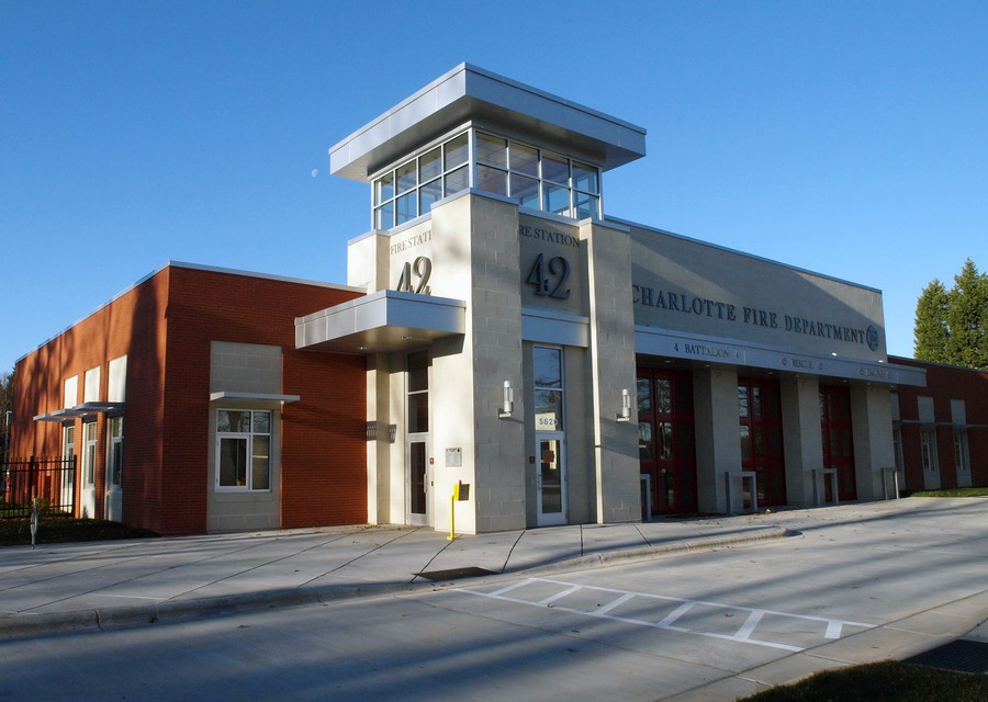 Exterior of a modern brick fire station with large apparatus bay doors and a central tower.