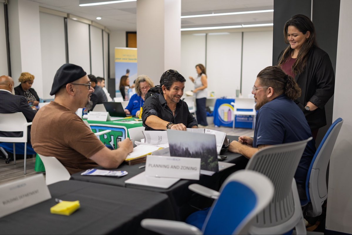 People seated at tables labeled Planning and Zoning and Building Department in a conference room.