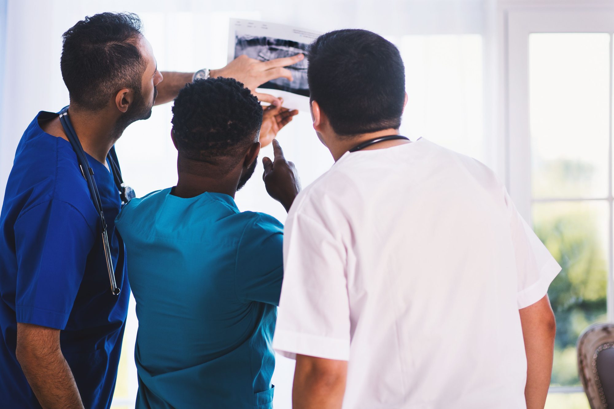 Doctors collaboratively analyzing an X-ray in a clinical setting, showcasing teamwork and medical expertise.