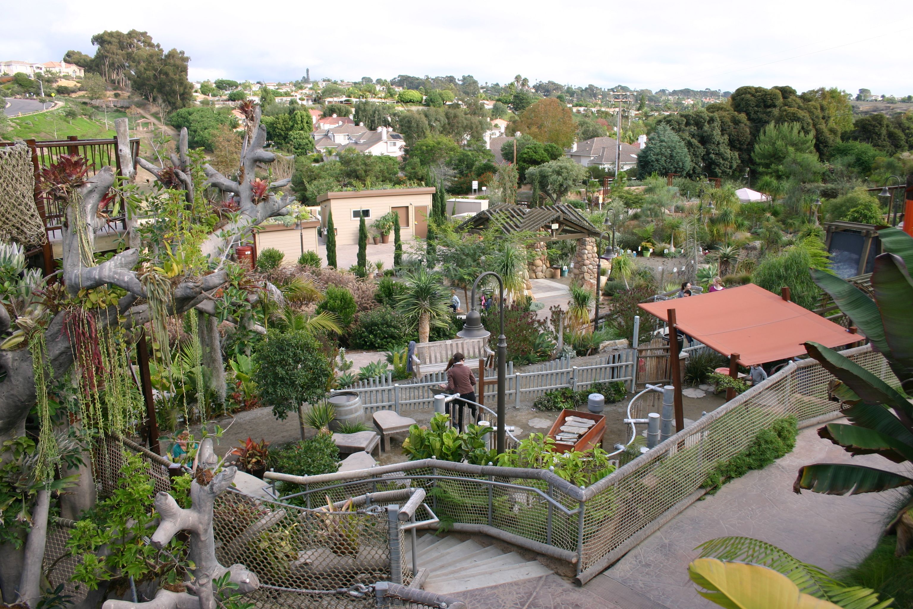 Aerial view of a lush botanical garden with terraced plantings, walking paths, and shade structures.