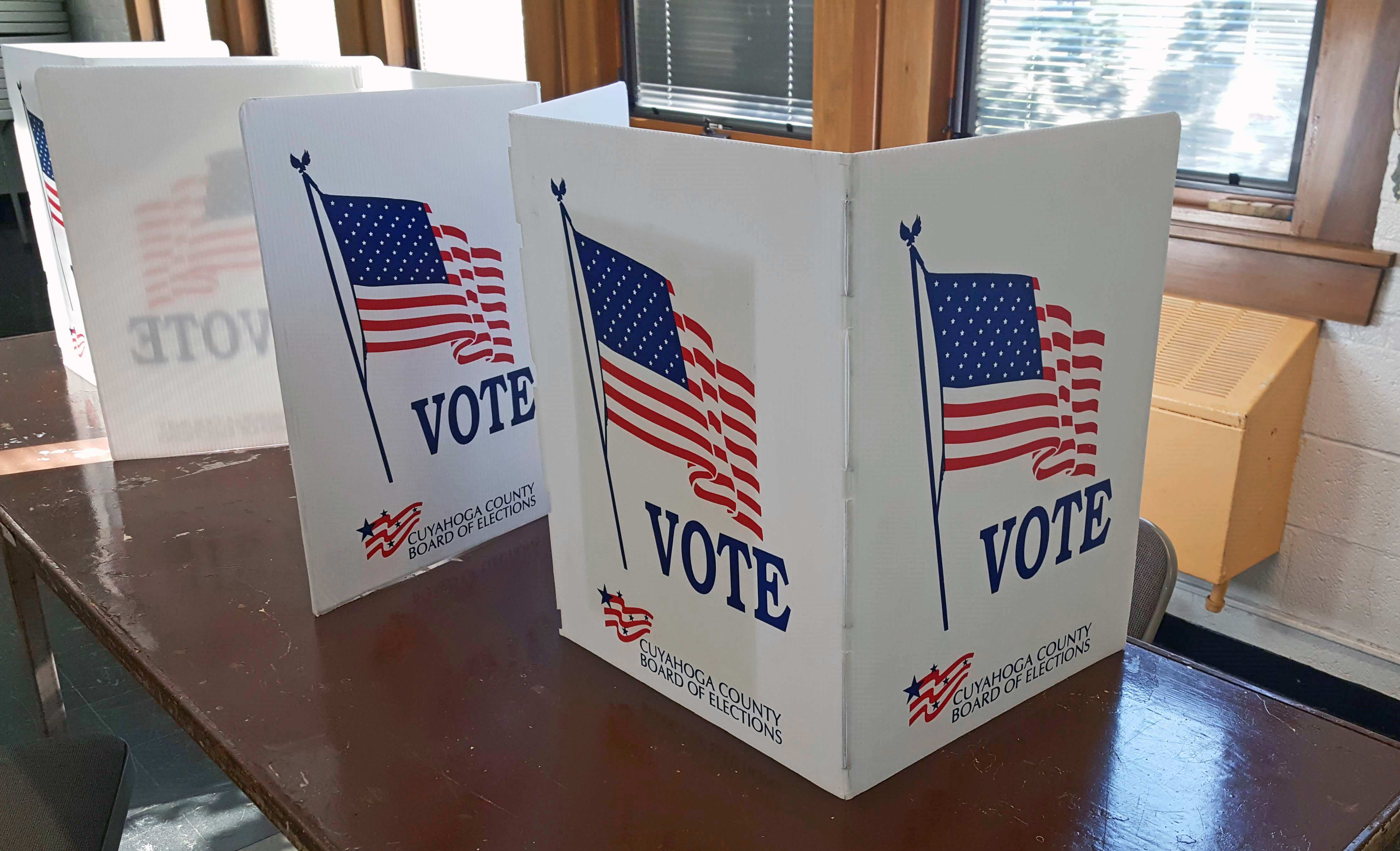 Three white tri-fold voting carrels on a table at an Ohio polling location.