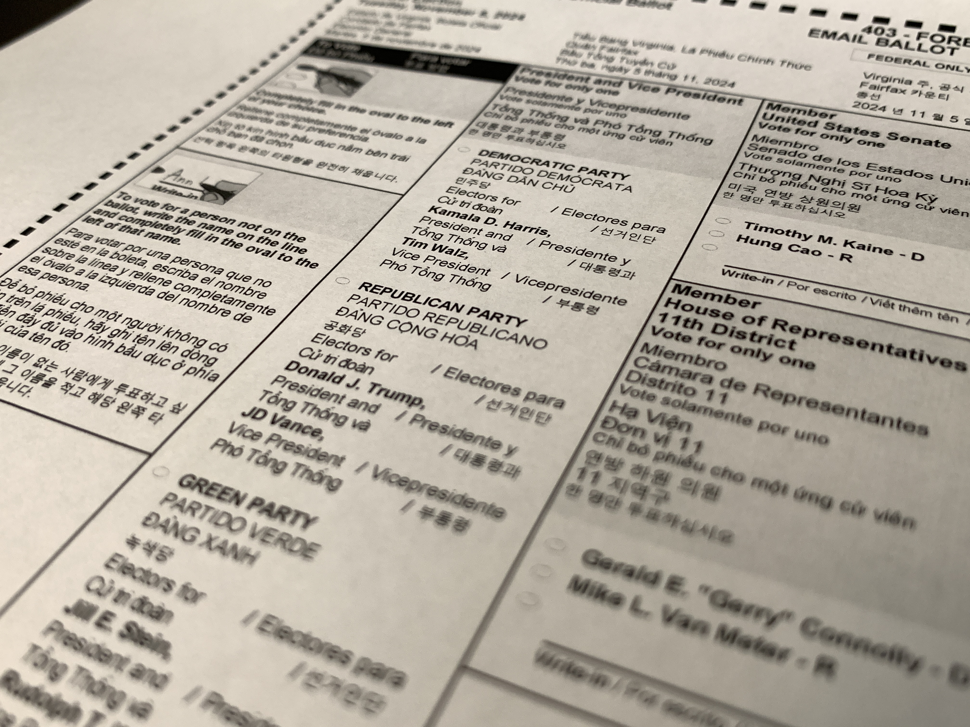 Close-up of a printed absentee mail ballot showing candidate names and multilingual text.