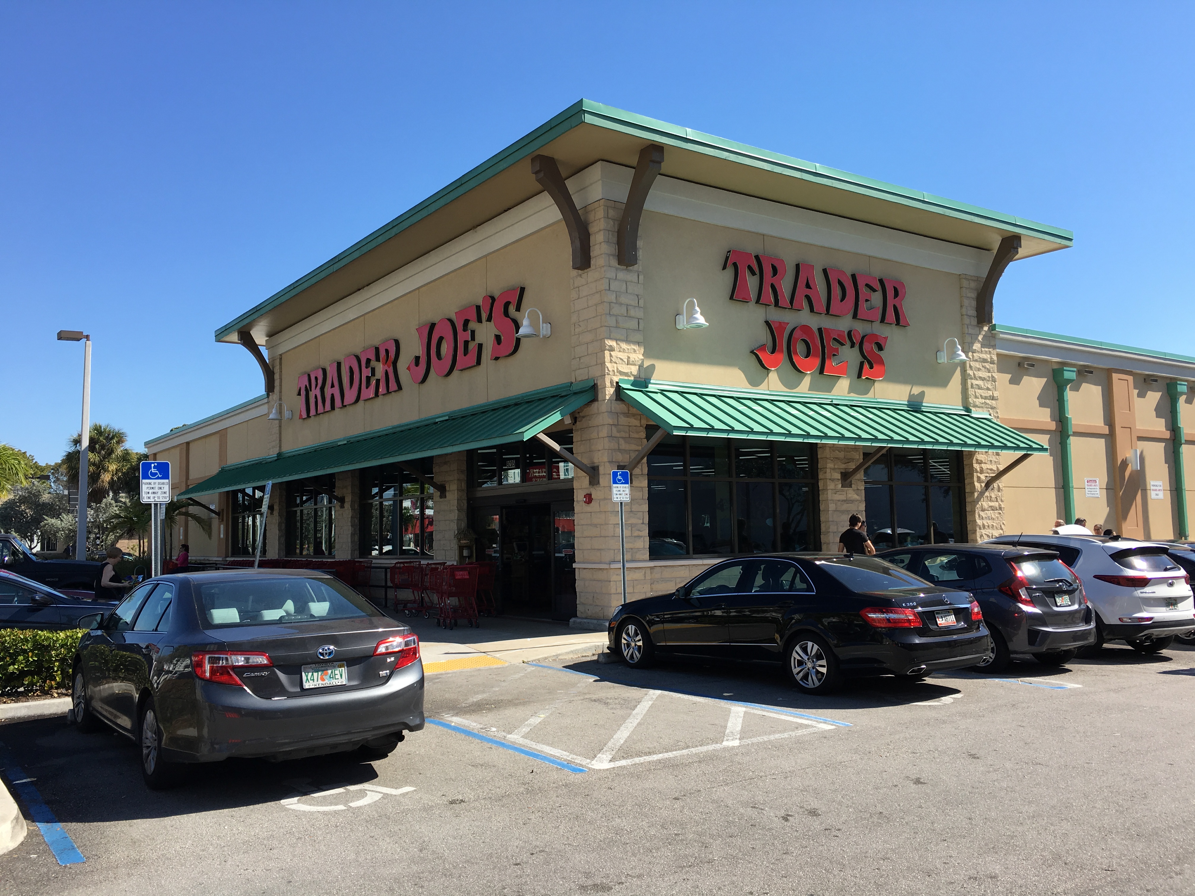 Exterior of a Trader Joe's grocery store with green awnings and a parking lot.