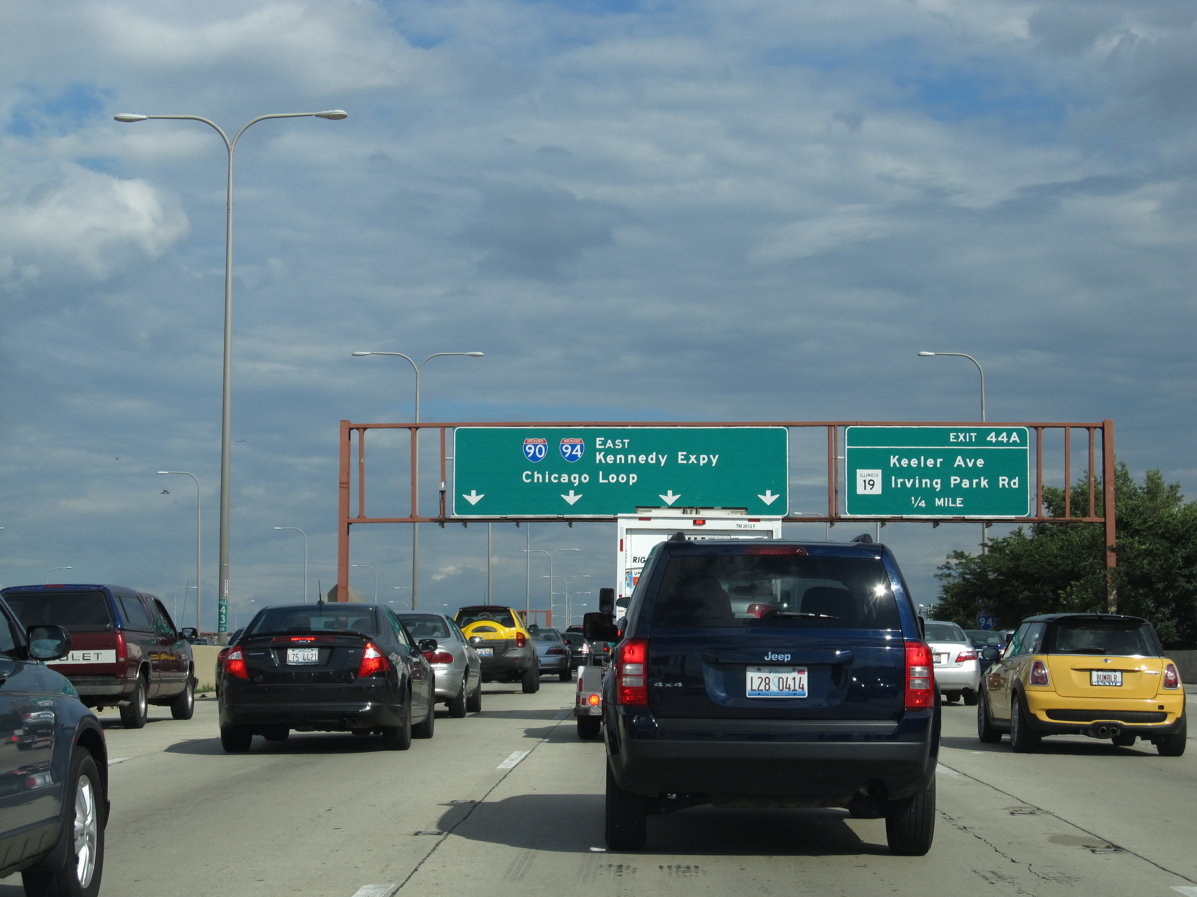 Bumper-to-bumper traffic on a multi-lane urban expressway under green overhead highway signs