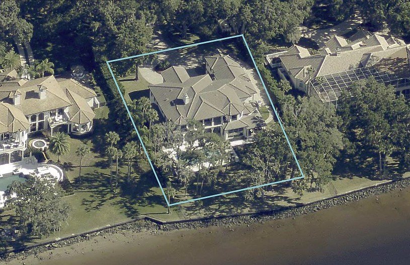 Aerial view of a large waterfront home with a pool and dock on a waterway lot.
