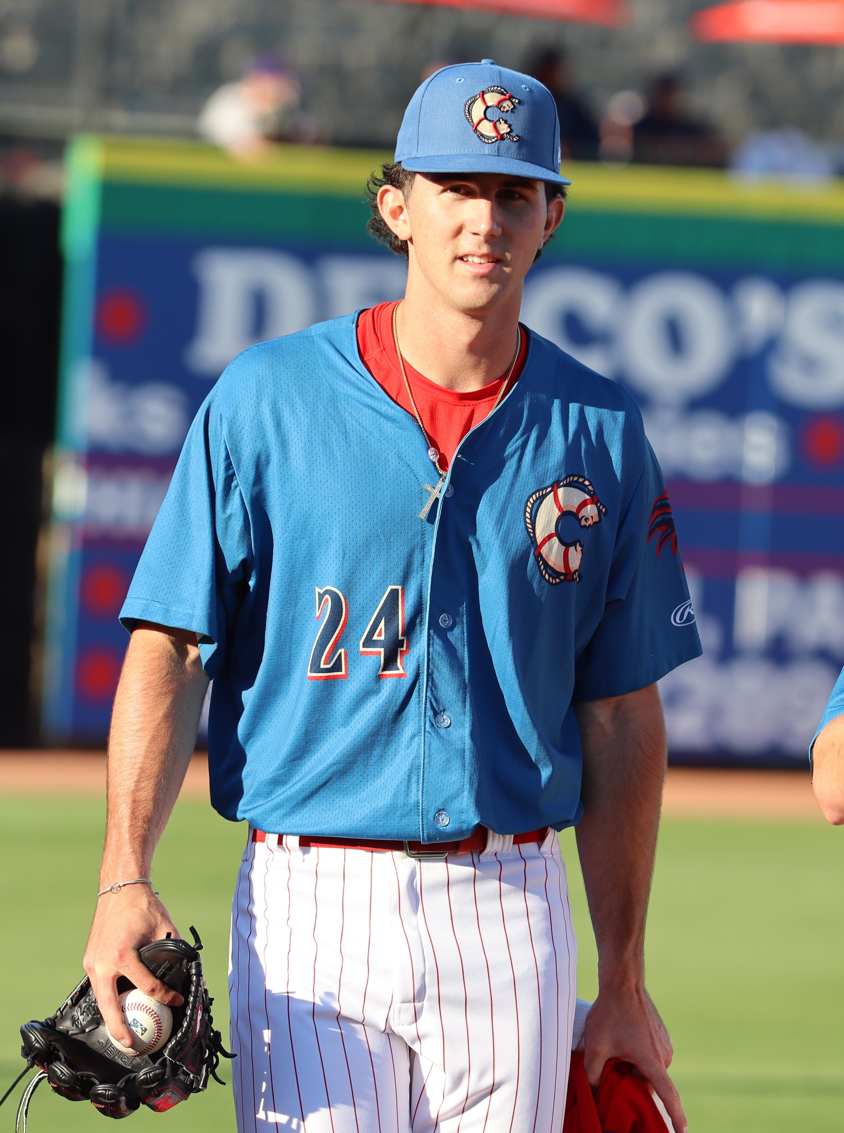 Baseball player in a blue Clearwater Threshers jersey holding a glove and ball on the field.