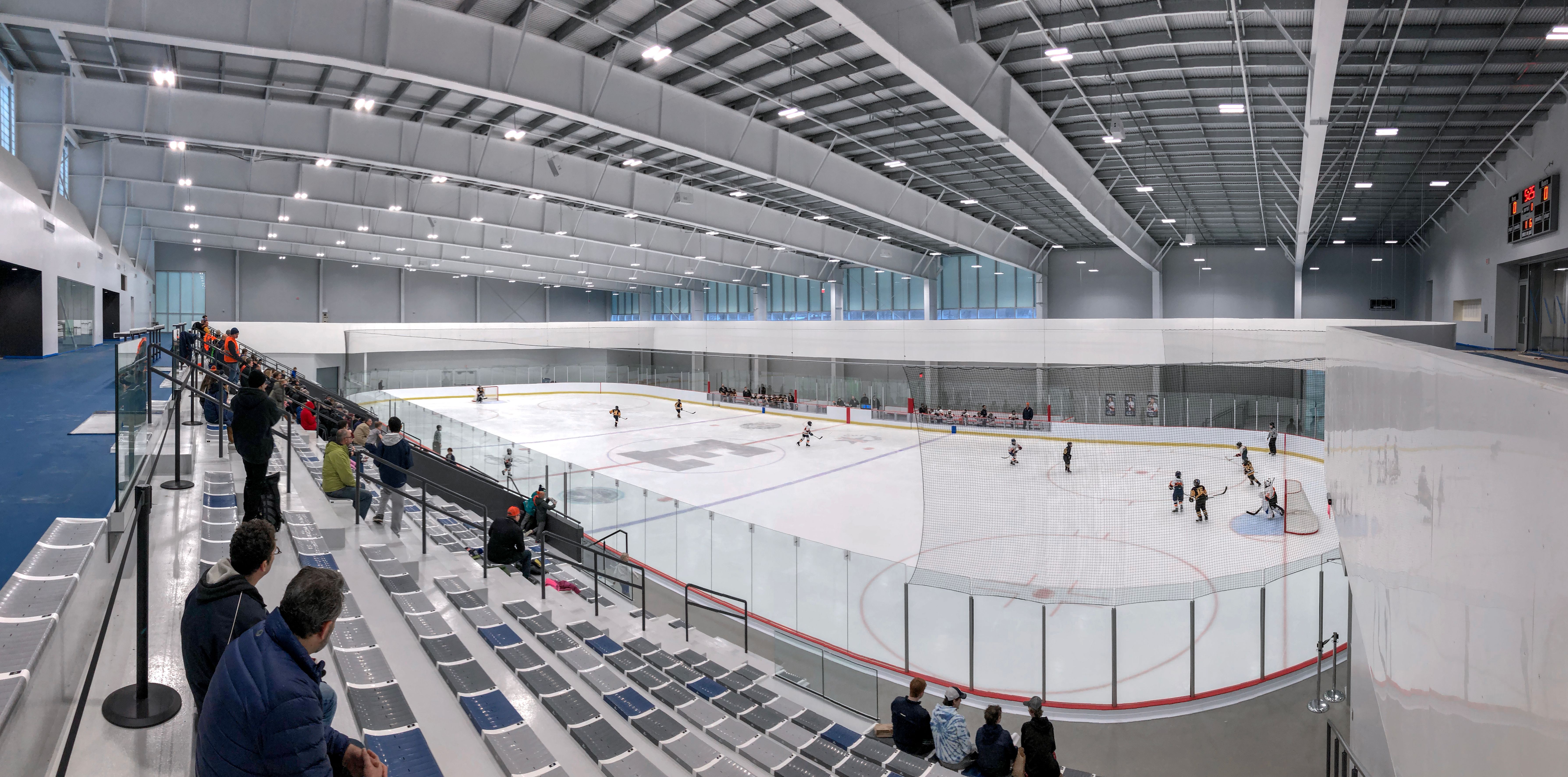 Interior of an indoor ice arena with a large ice surface and spectators in the stands.