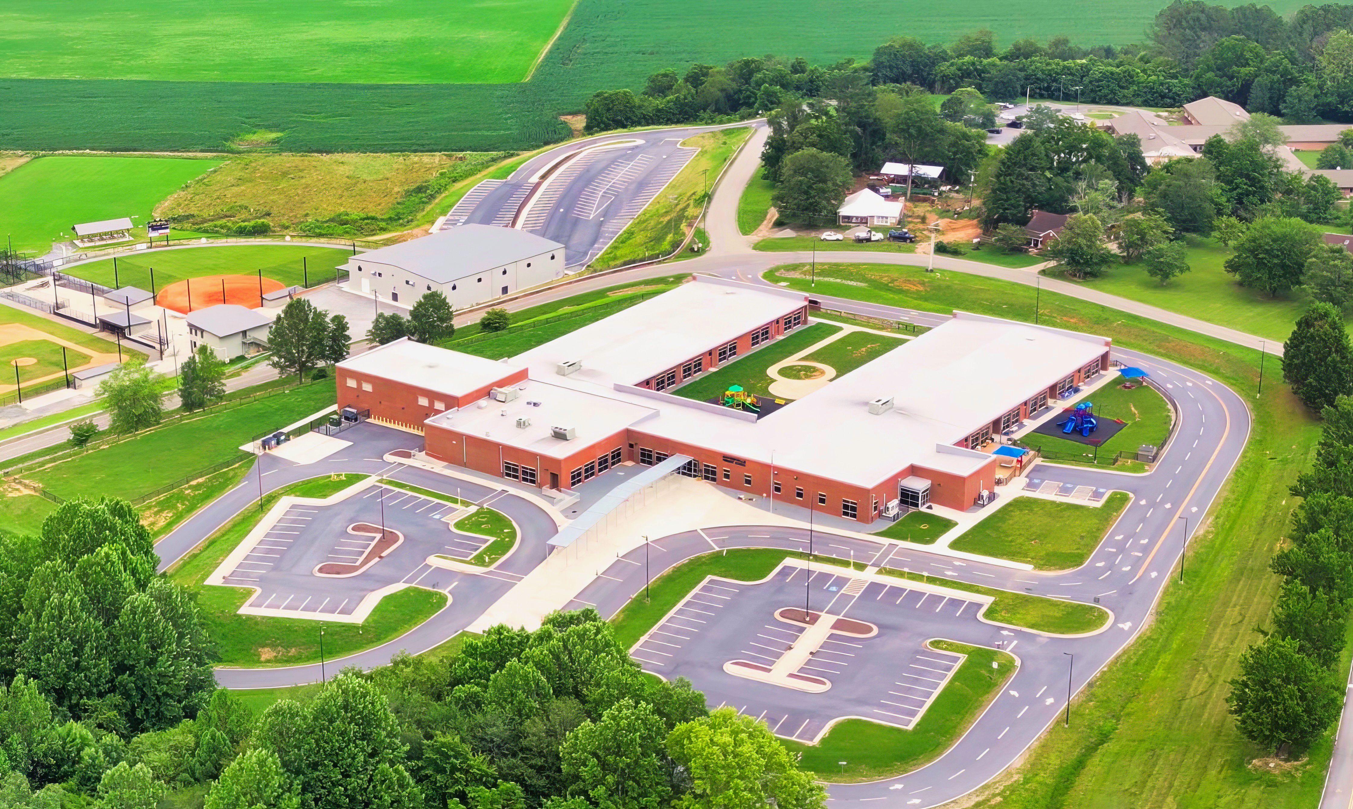 Aerial view of a single-story brick school campus with parking lots and green fields.