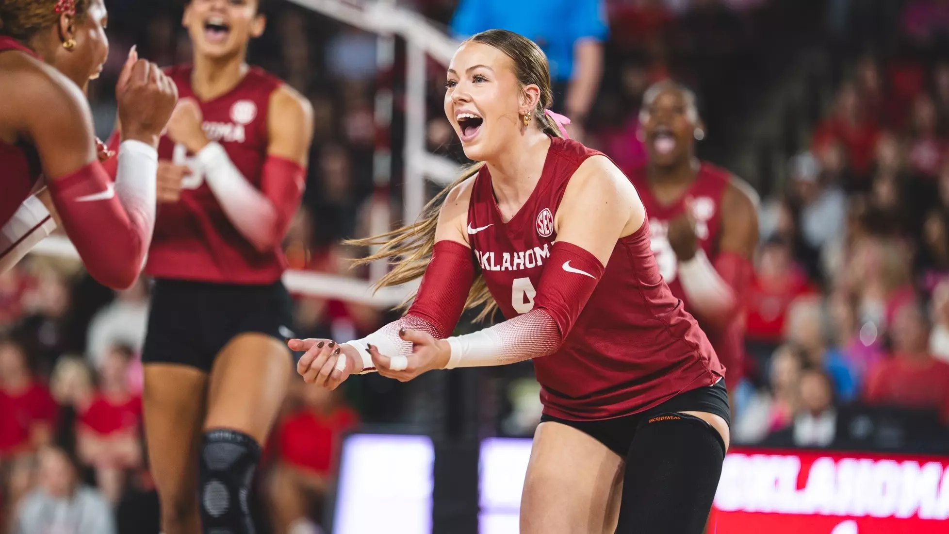 A volleyball player in an Oklahoma Sooners uniform celebrates on the court.