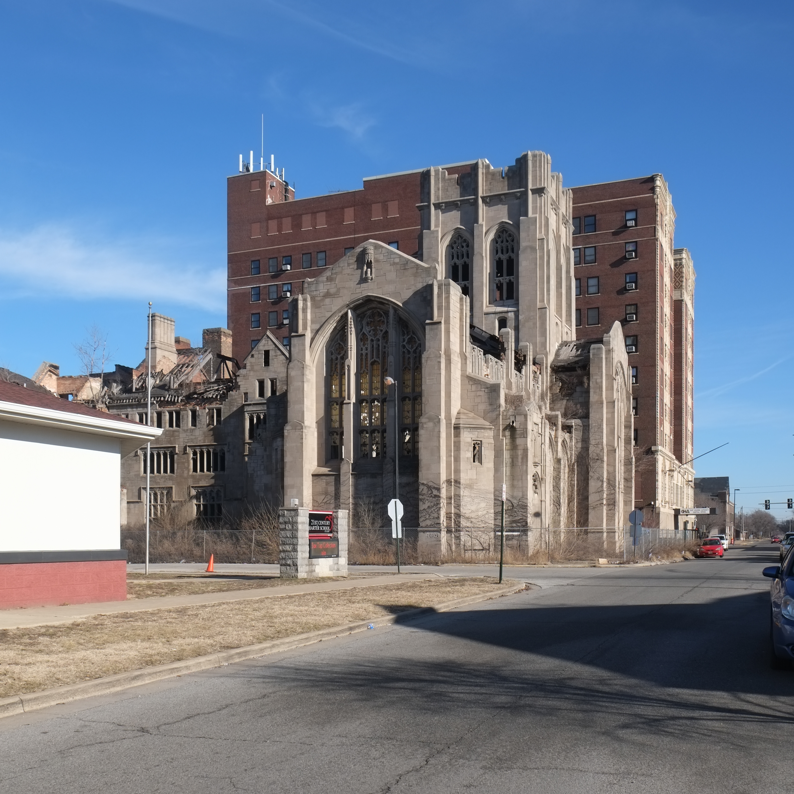 Gothic stone church facade with collapsed roof and empty arched windows on a city street.