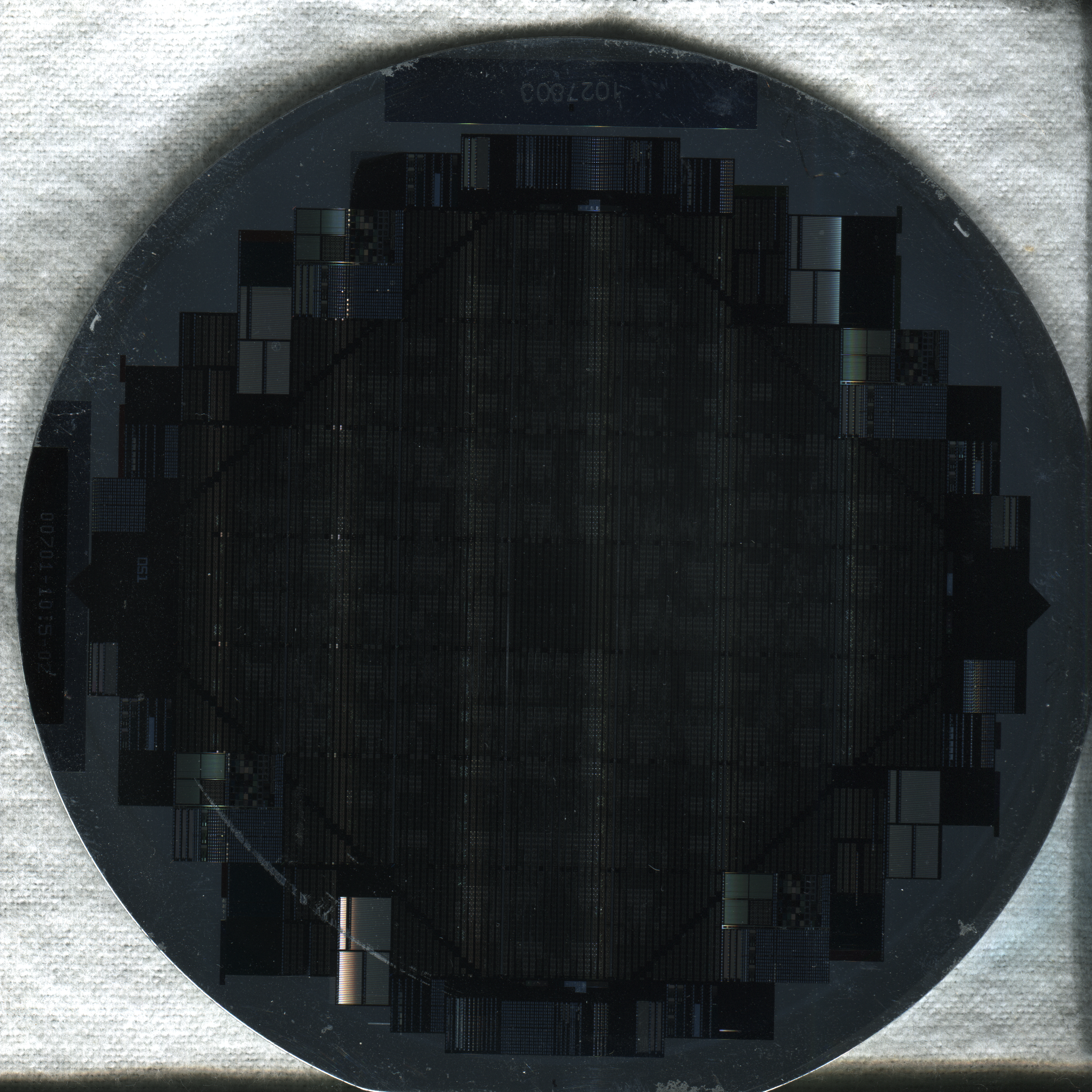 Circular semiconductor wafer with a grid pattern of integrated circuit dies.