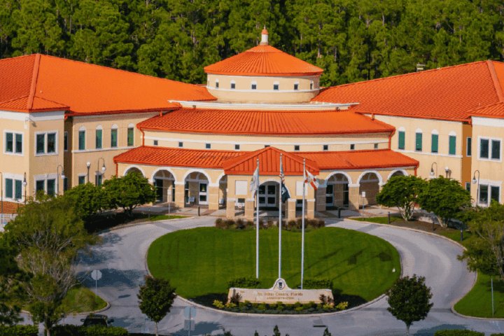 Aerial view of a large government building with terracotta tile roofs and a circular driveway.