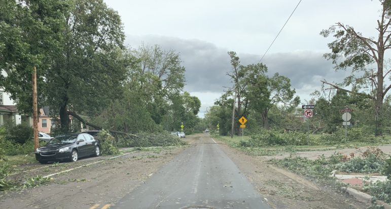 Fallen tree branches and debris blocking a residential street after a derecho storm.
