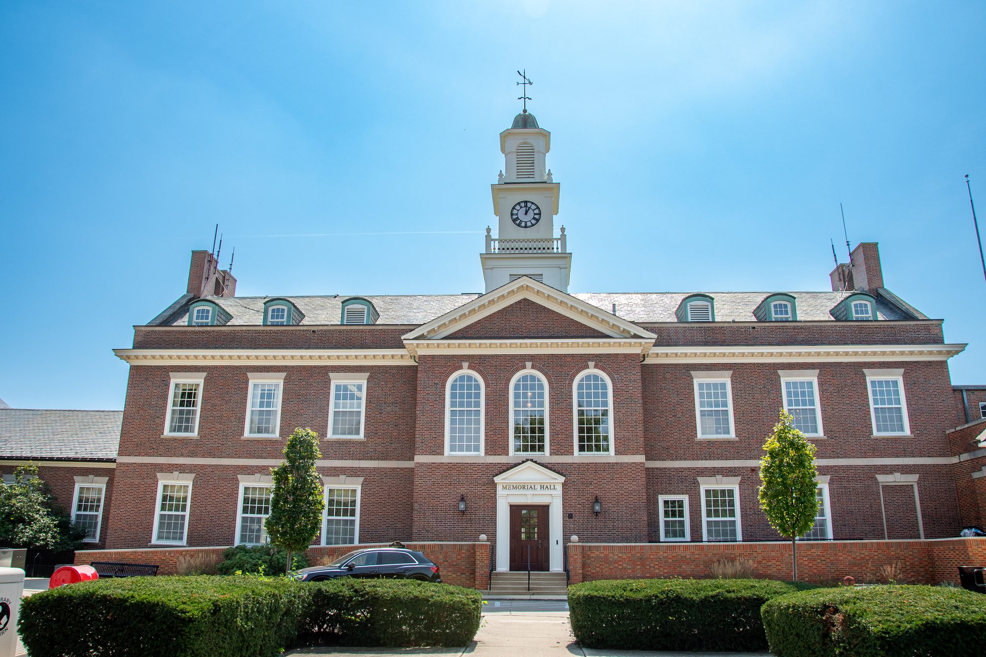 Historic brick building with clock tower and columned entrance on a sunny day