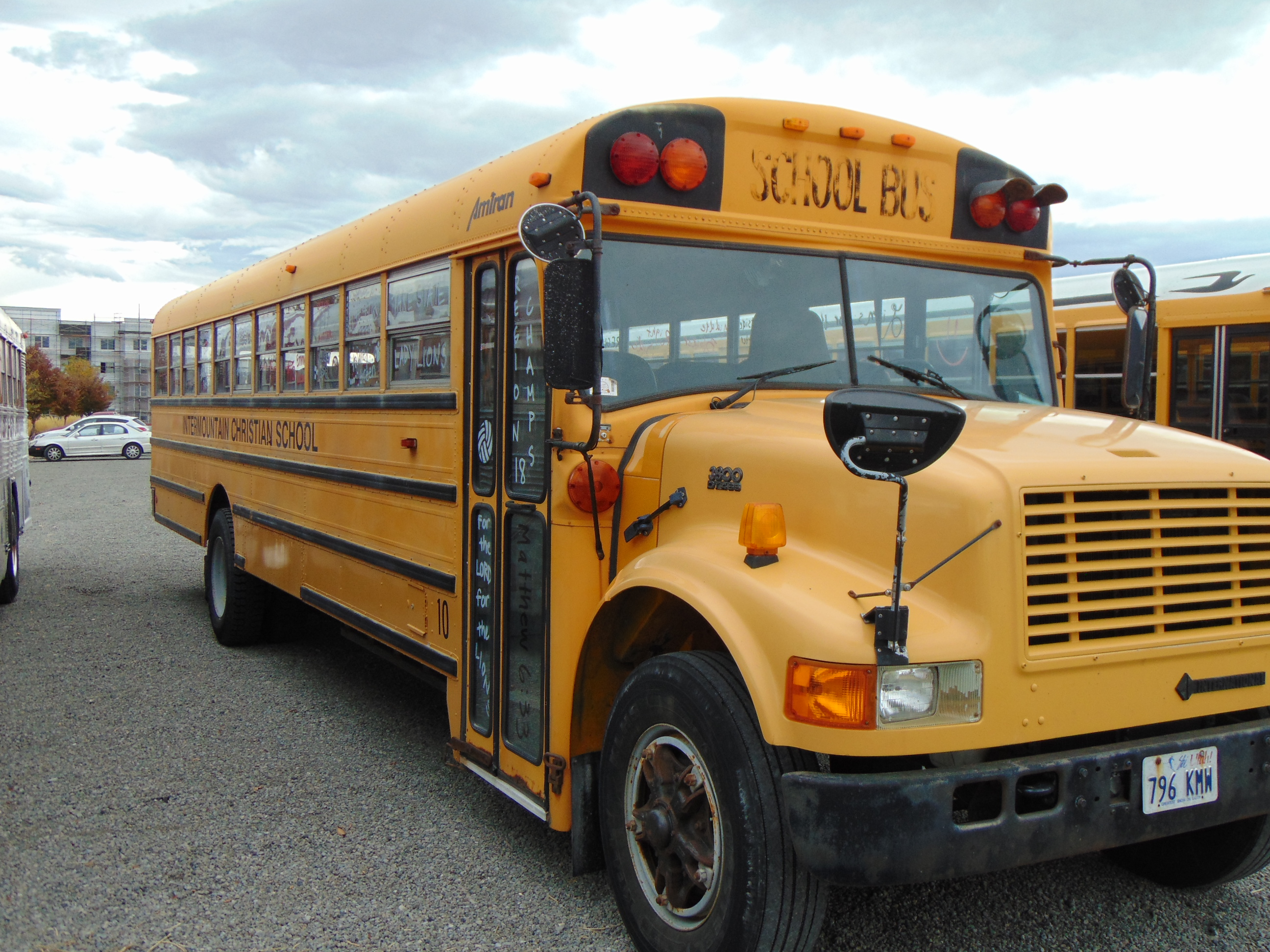 A yellow school bus parked in a lot, viewed from a front three-quarter angle.