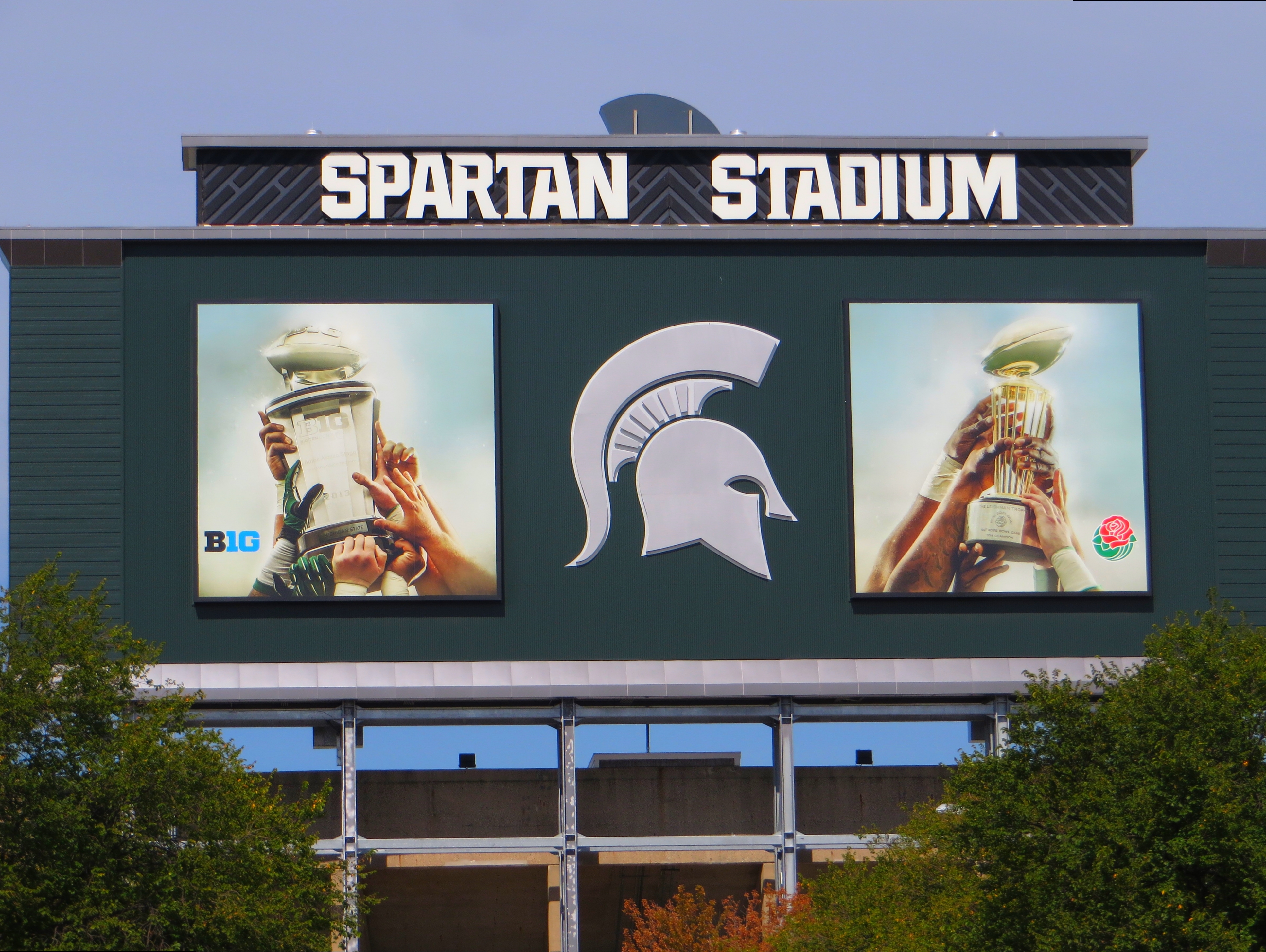 Spartan Stadium scoreboard facade displaying the Spartan helmet logo, Big Ten branding, and two video screens.