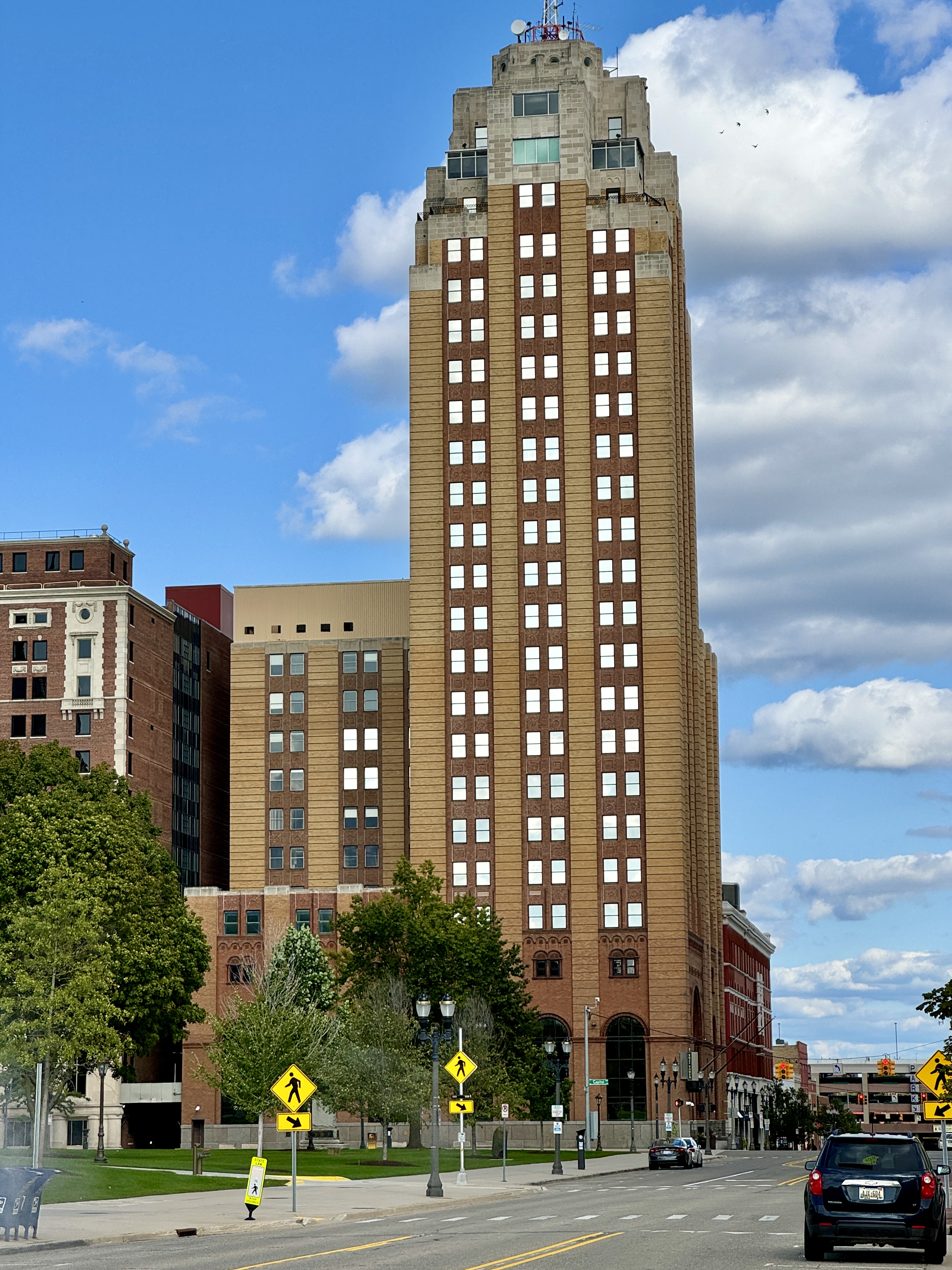 Tall Art Deco skyscraper at a downtown intersection with pedestrian crossing signs visible.