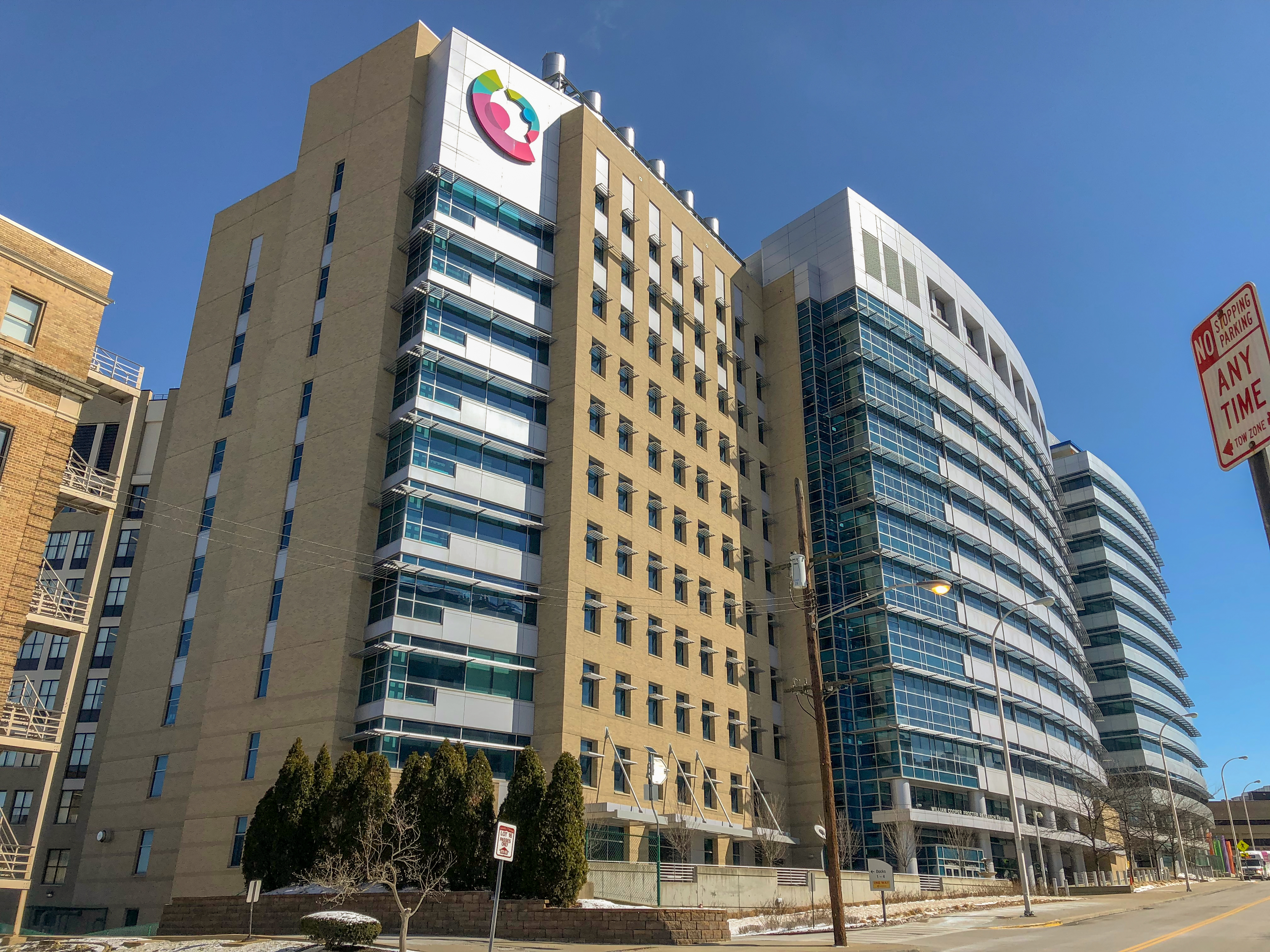 Exterior of a large hospital building with a colorful circular logo on its facade.