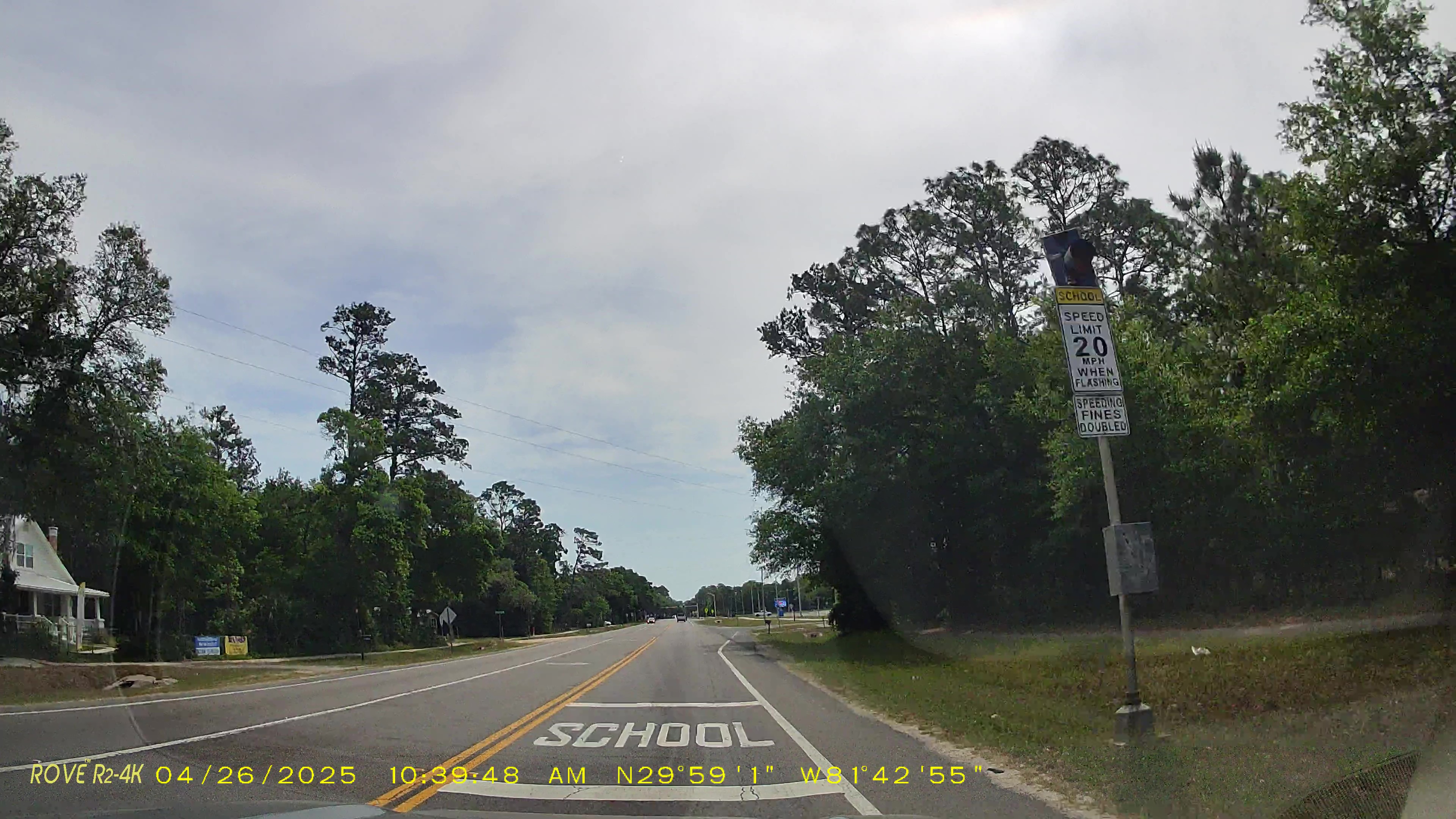 Yellow 20-mph school zone speed limit sign beside a two-lane road.