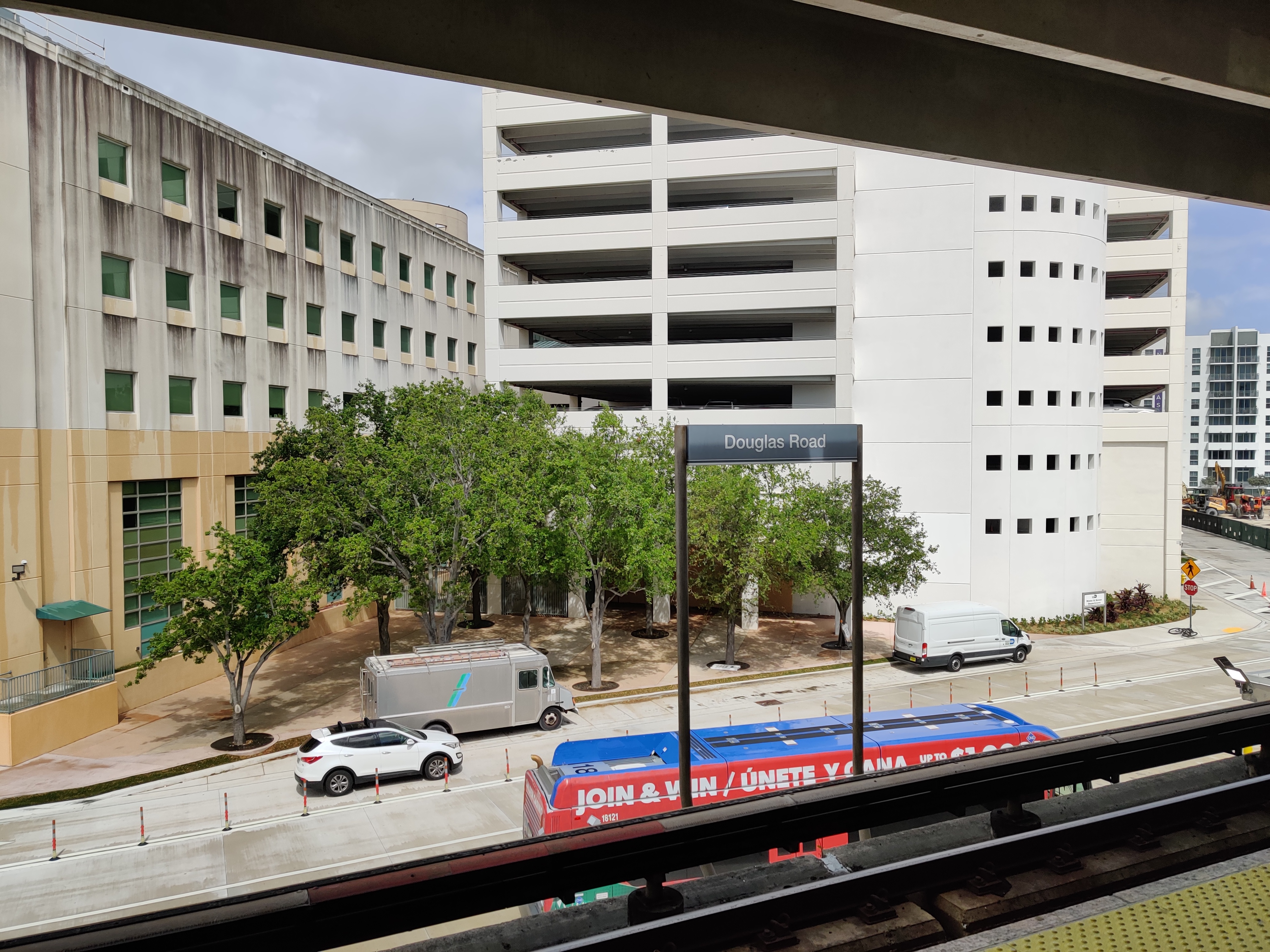 Elevated Metrorail station sign and train visible below the platform structure.