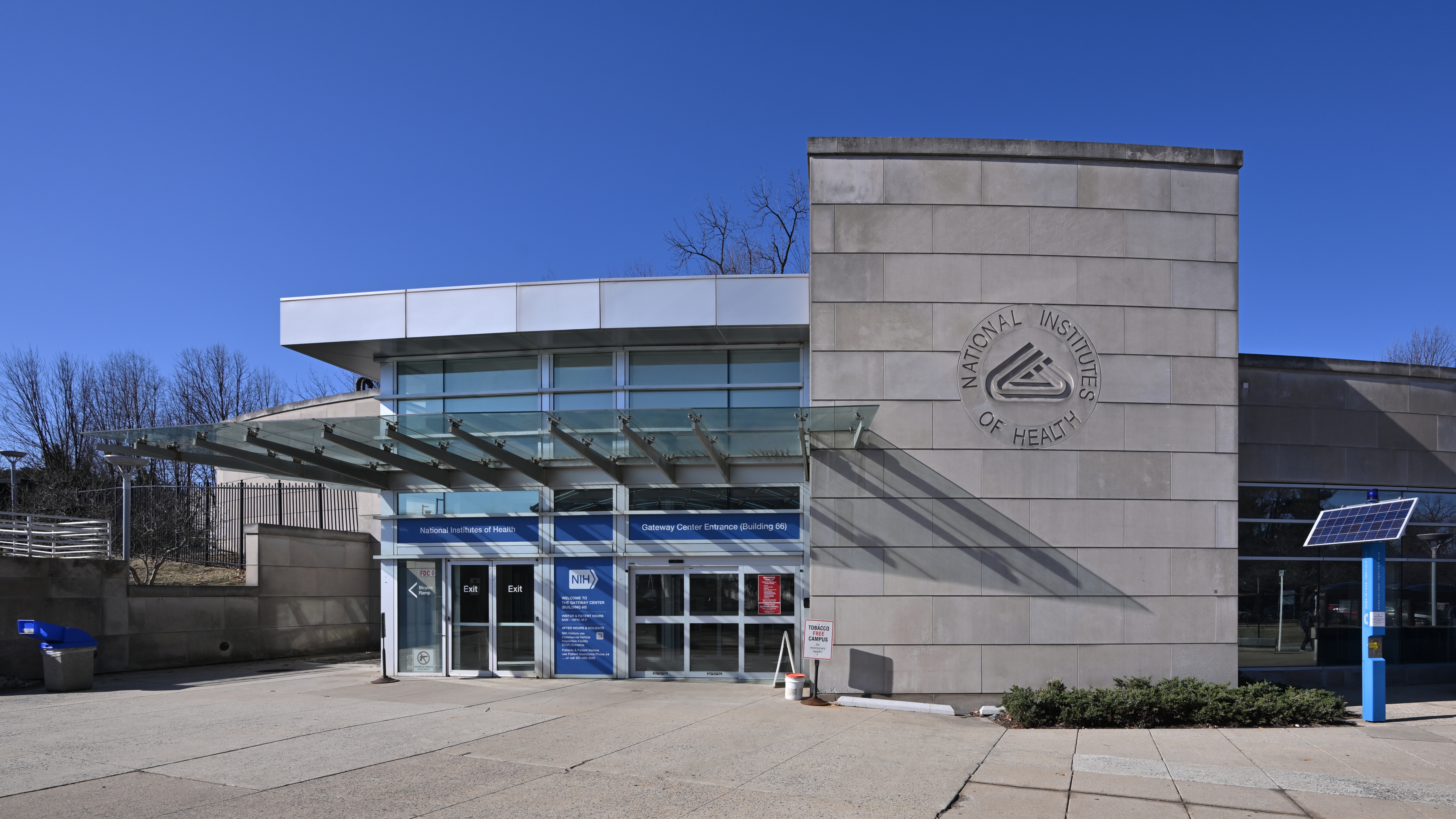 Modern glass-and-stone entrance building with the NIH seal on its facade.