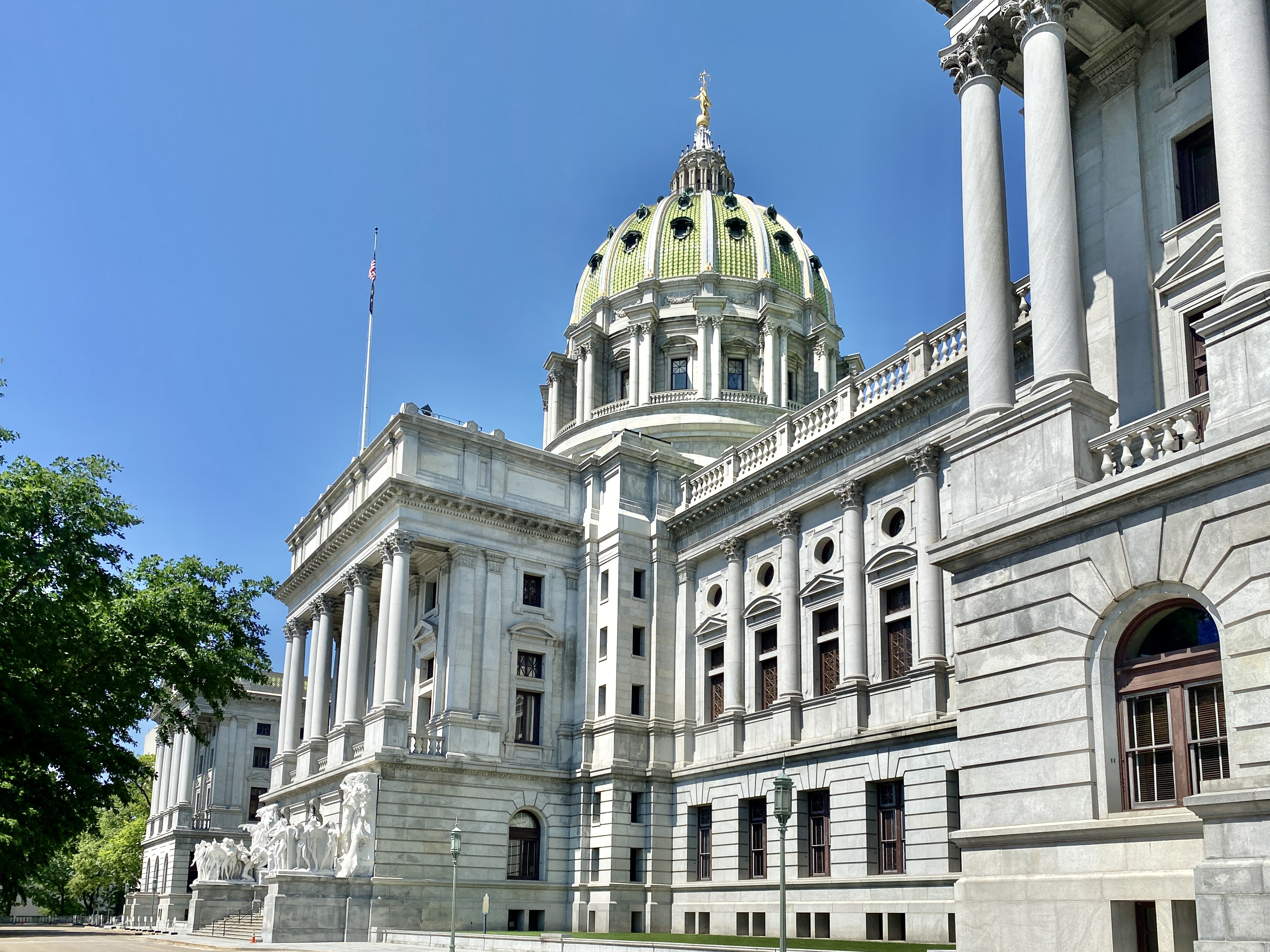 Pennsylvania State Capitol building with green dome and golden statue under blue sky