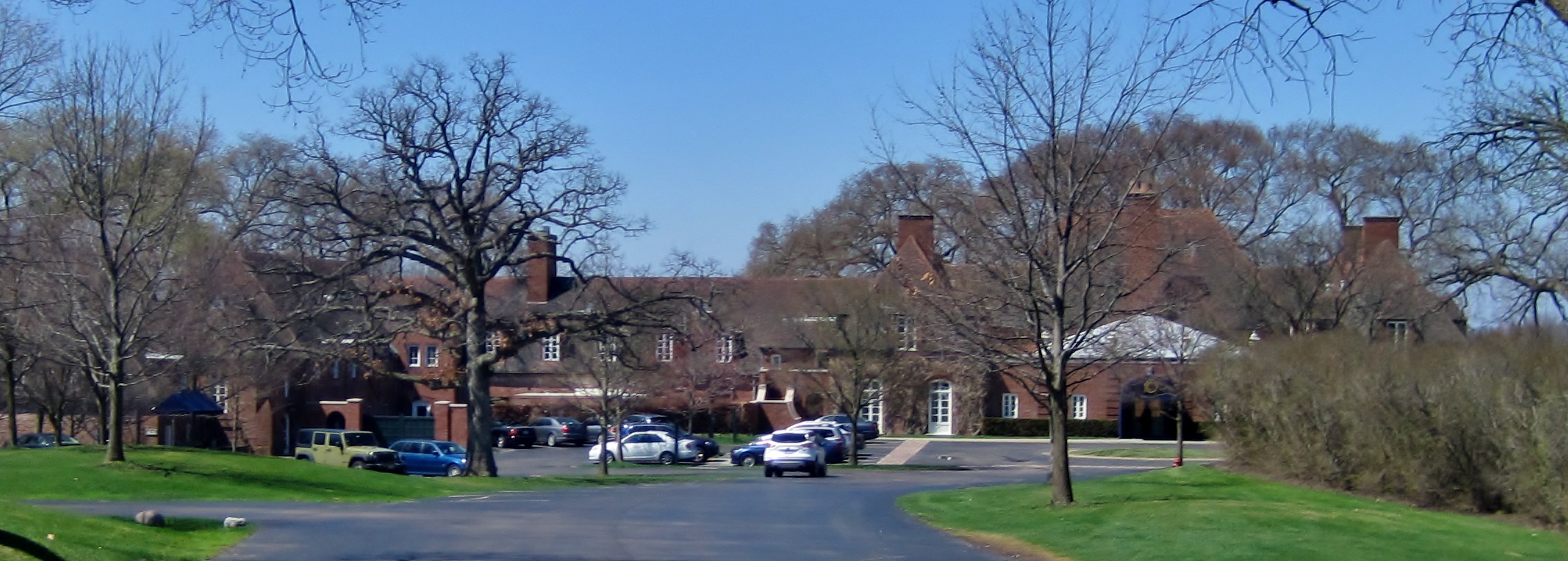 Brick Tudor-style clubhouse surrounded by bare trees on a clear day.
