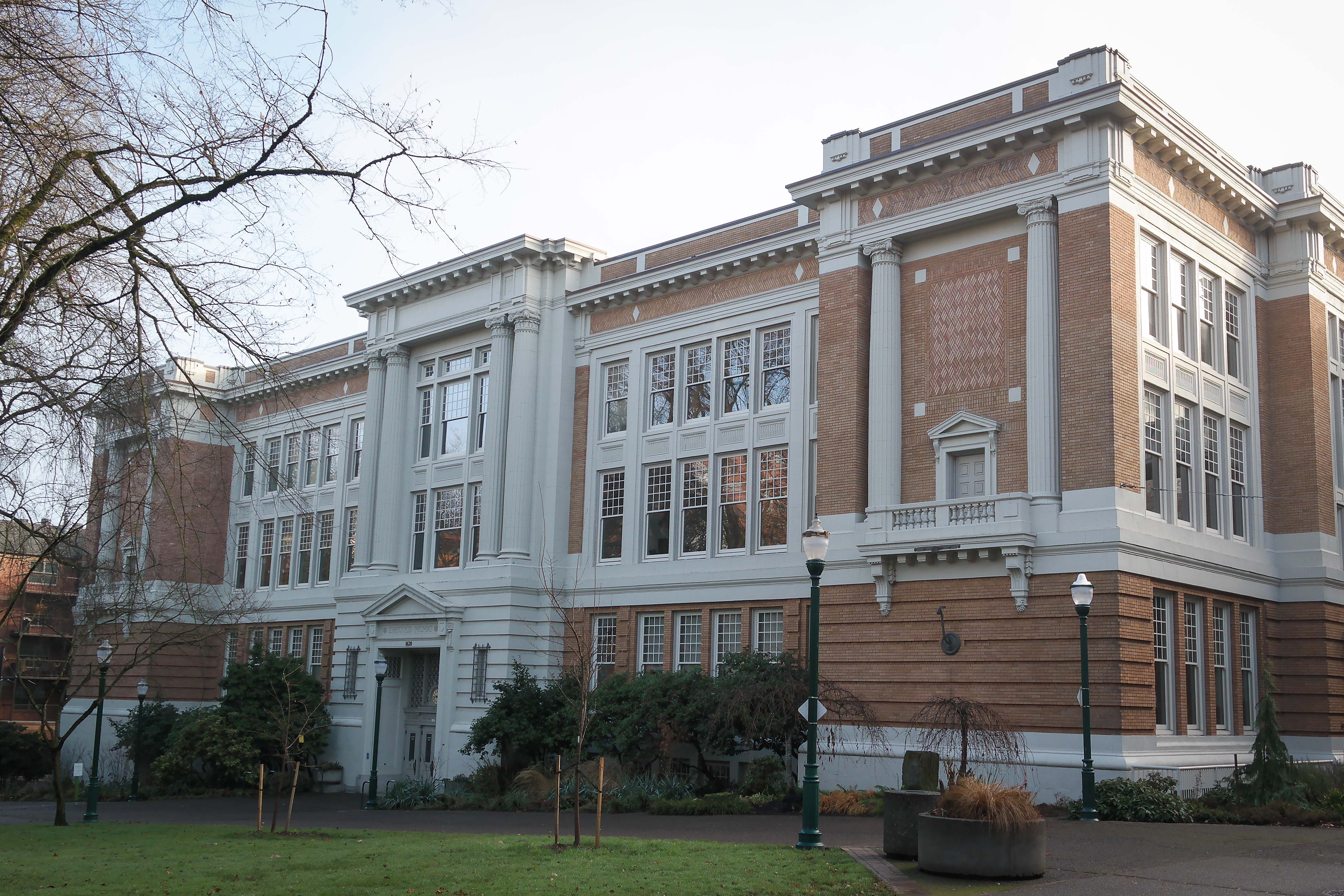 Classical brick academic building with white columns and street lamps on a university campus.
