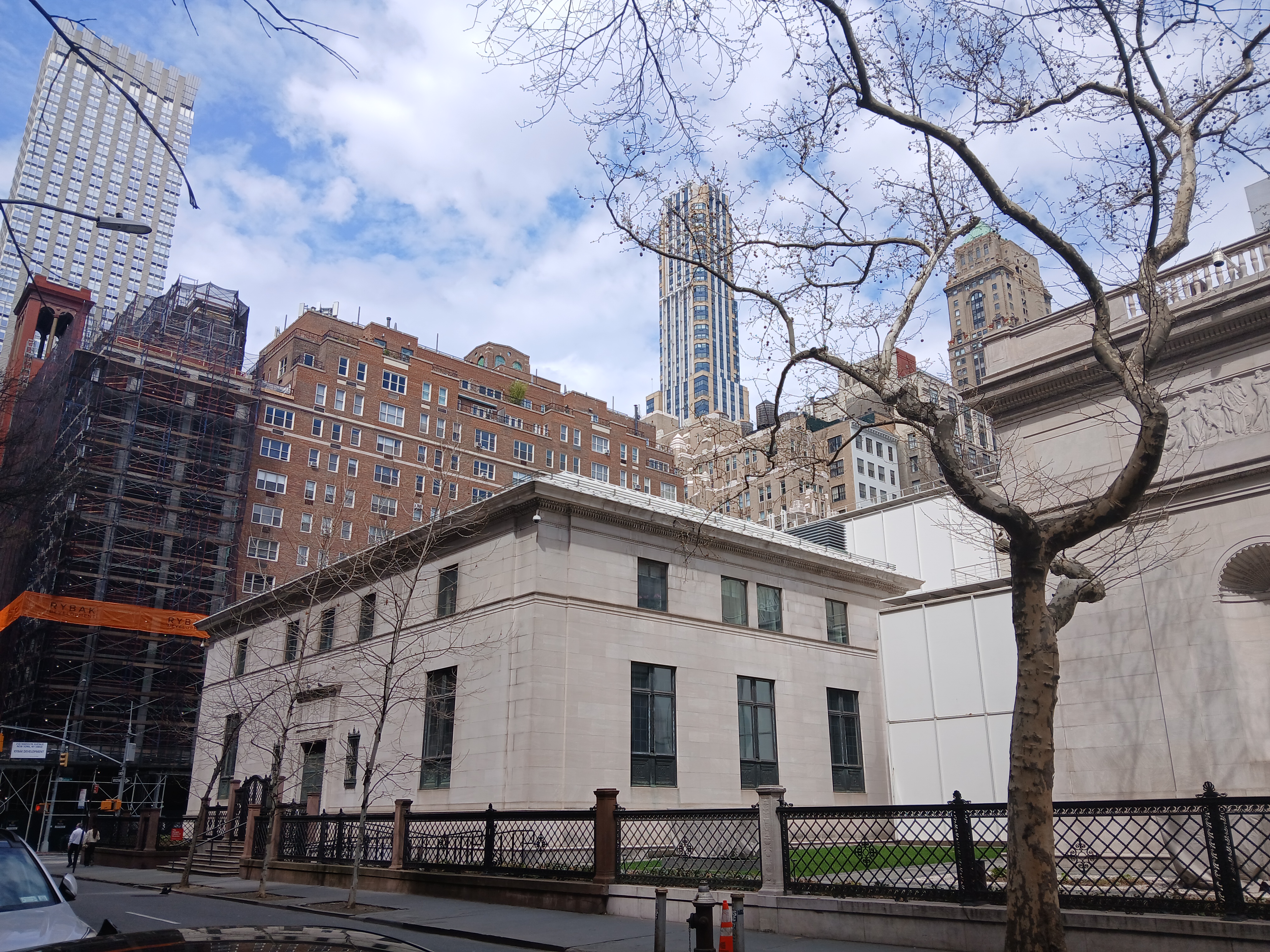 Neoclassical stone building with iron fence and bare trees on a Manhattan street.