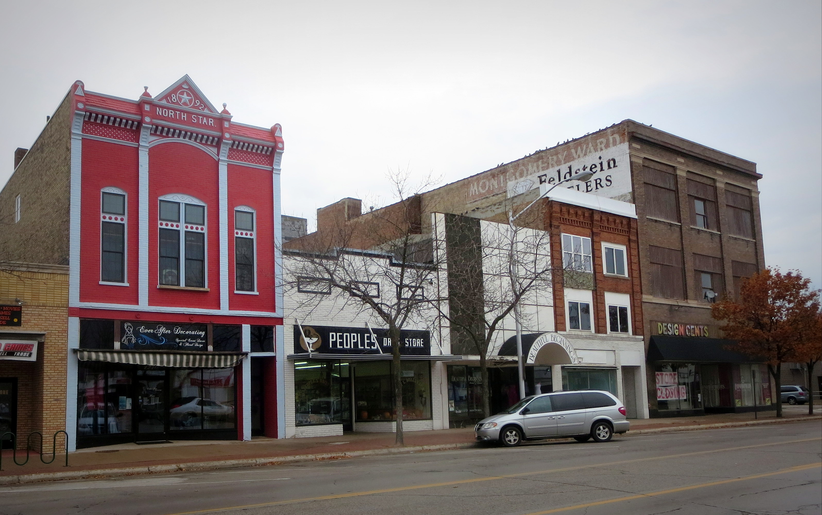 Row of historic brick storefronts lining a downtown street on an overcast day.