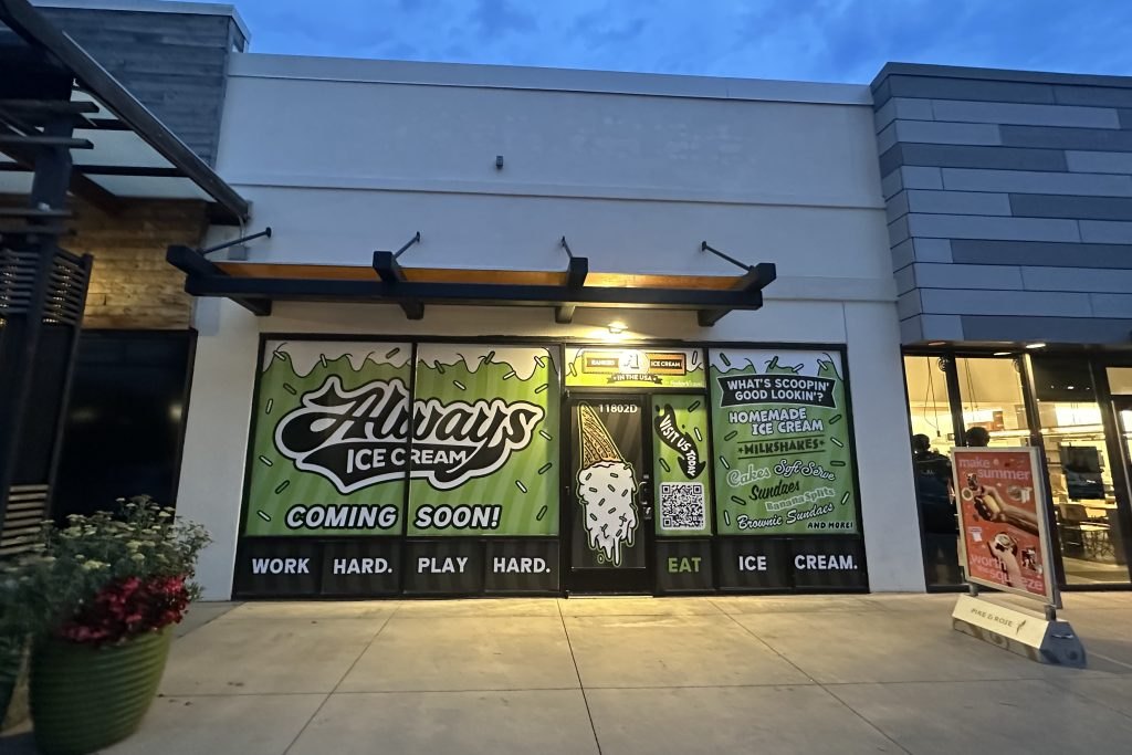Storefront window with Always Ice Cream Coming Soon signage at dusk in a shopping center.