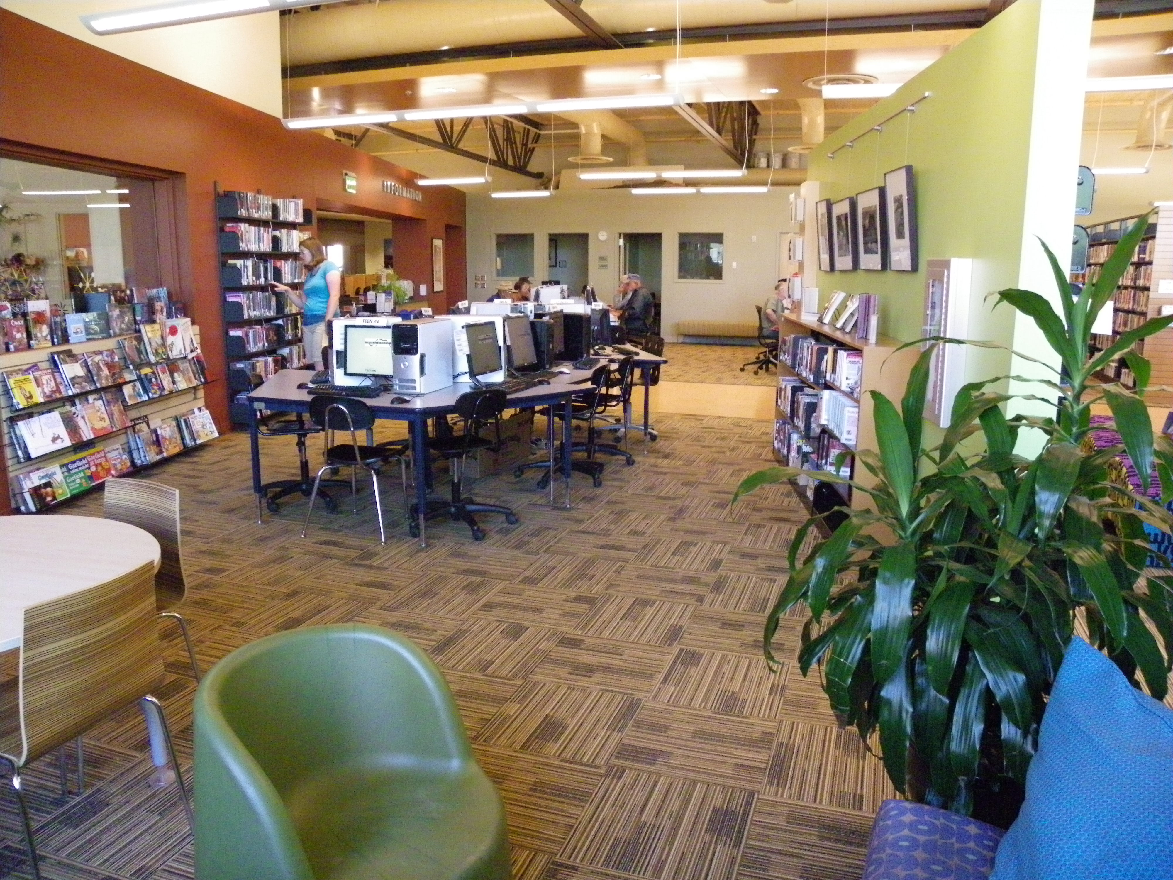 Interior of a public library with computer workstations, bookshelves, and patrons.