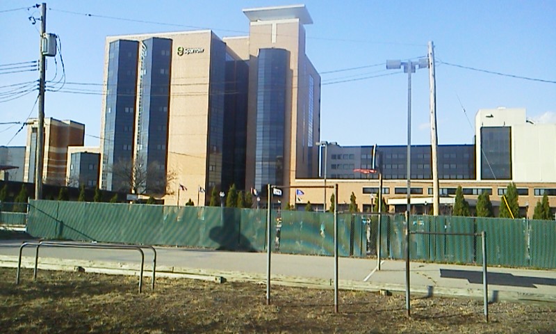 Multi-story hospital complex with glass and brick facades under a blue sky.