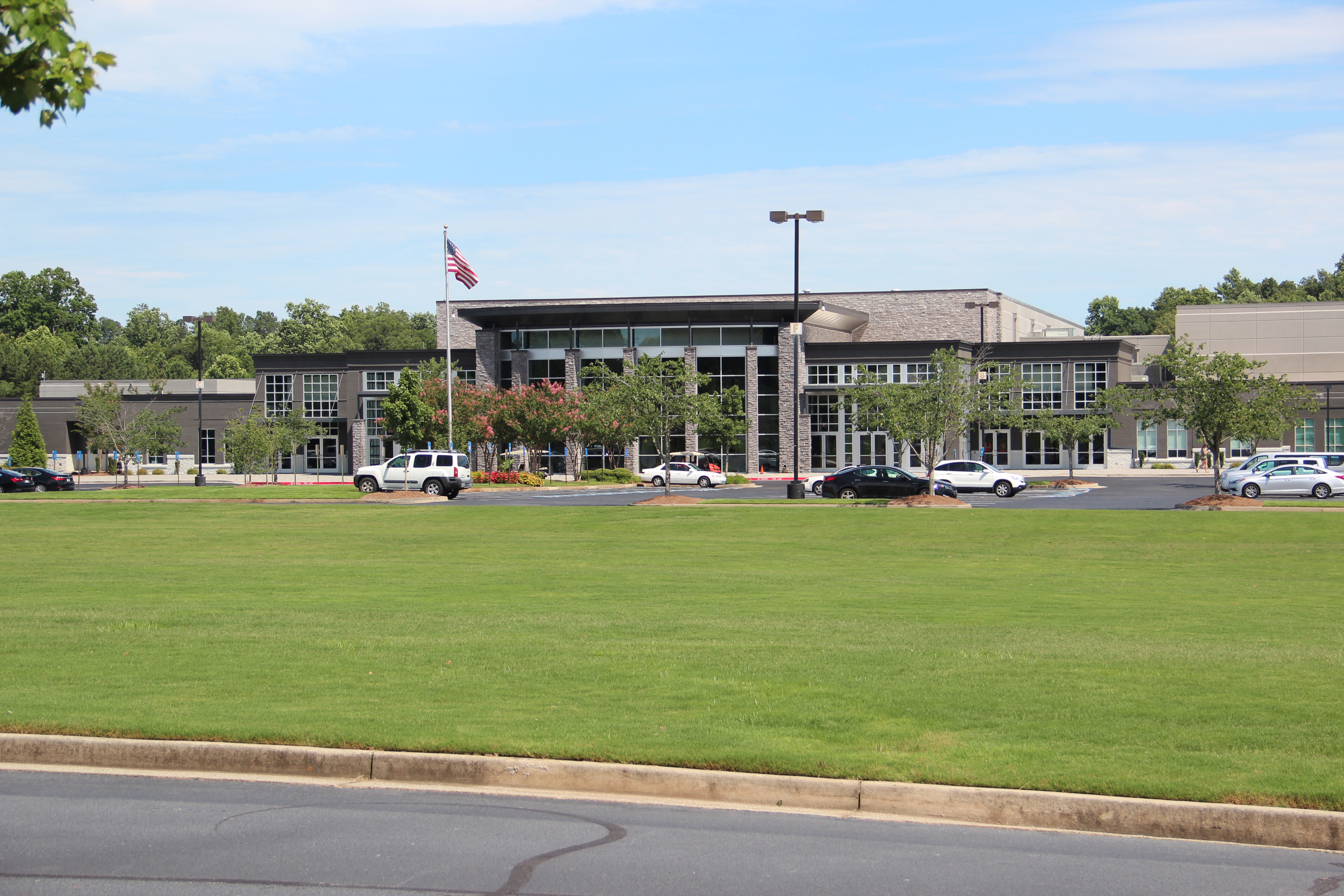 Modern glass-fronted church building with flagpole and manicured lawn.