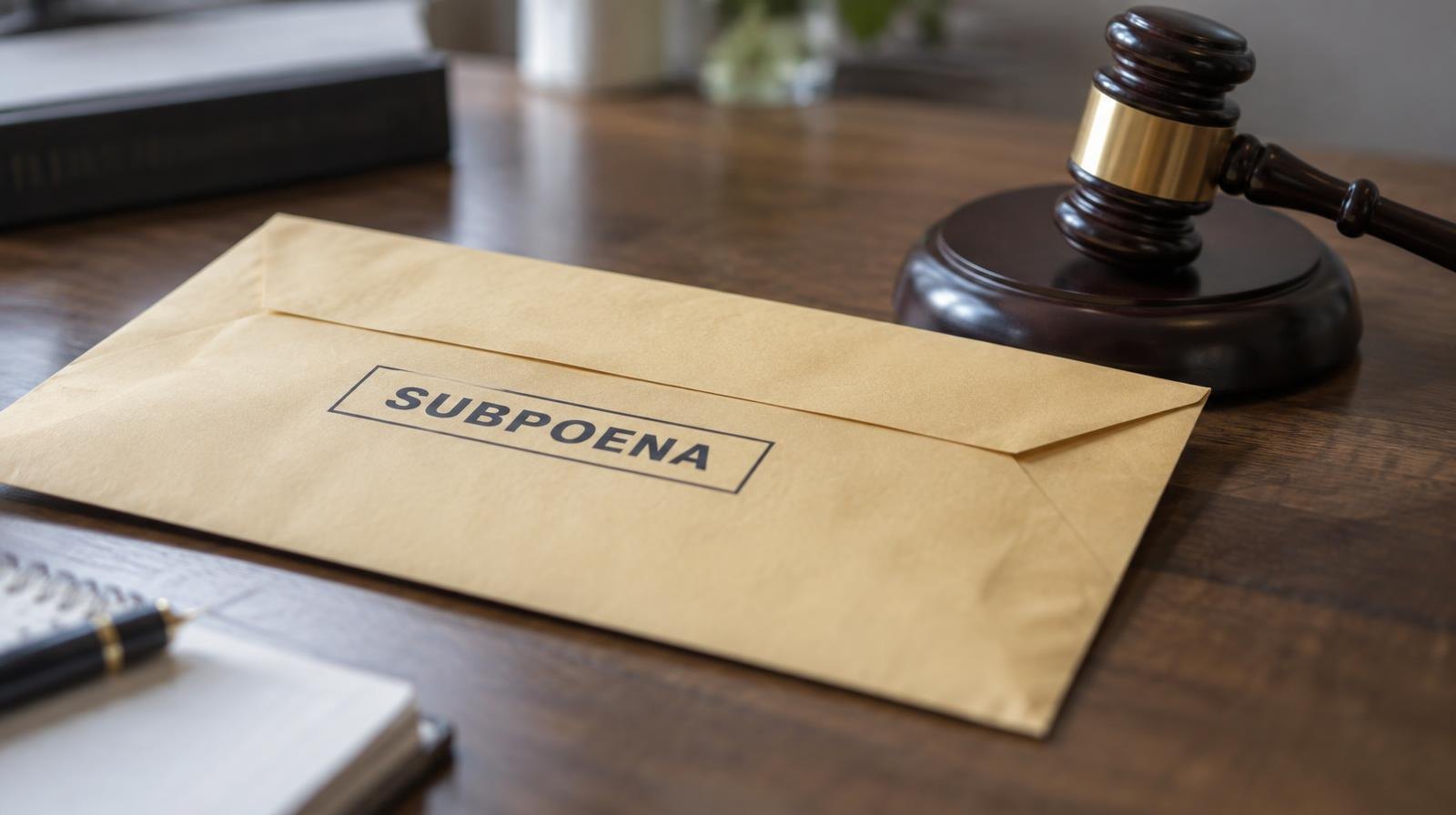 A sealed manila envelope and wooden gavel resting on a wooden desk.