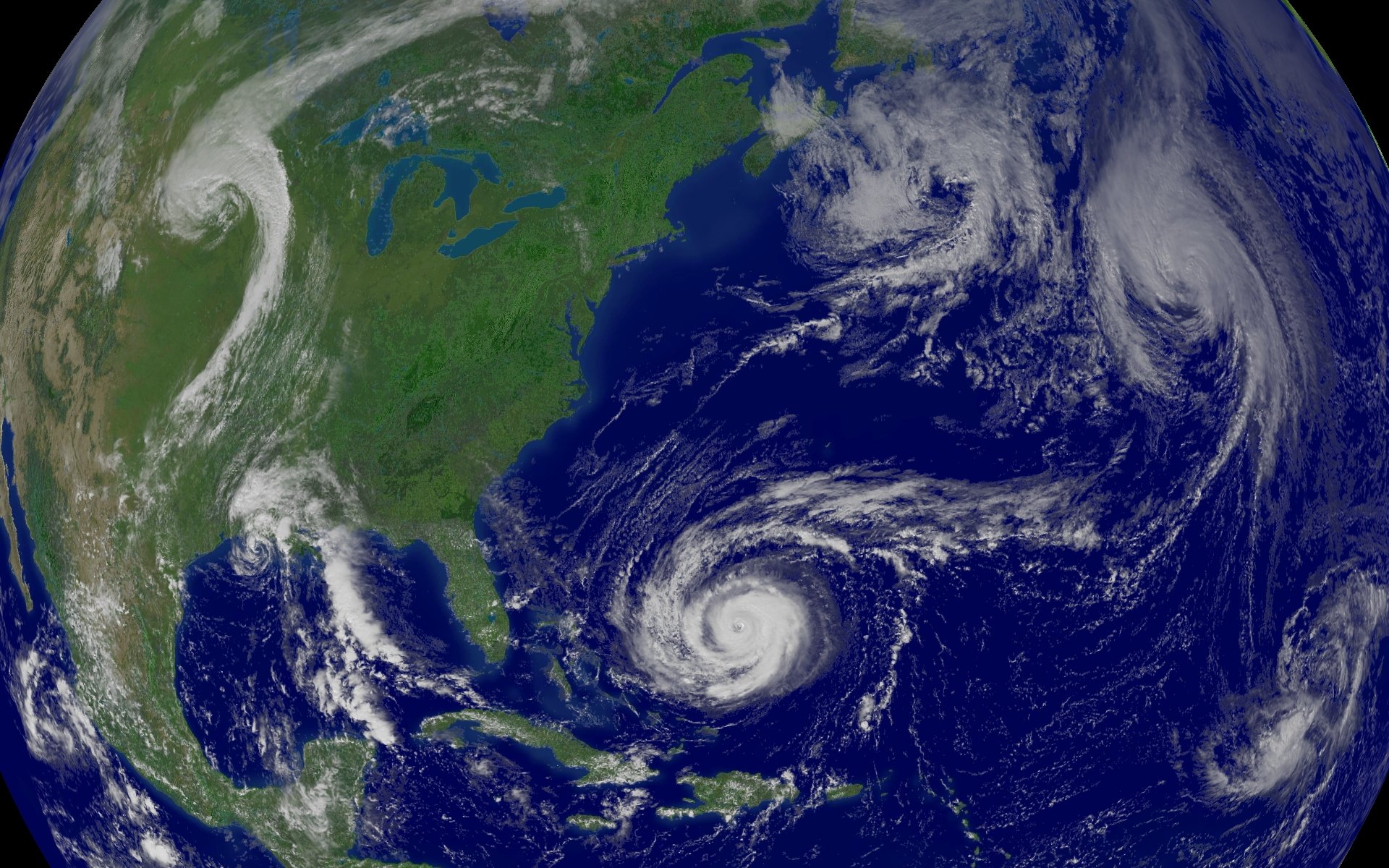 Satellite view of the Atlantic Ocean showing several swirling tropical storm systems.
