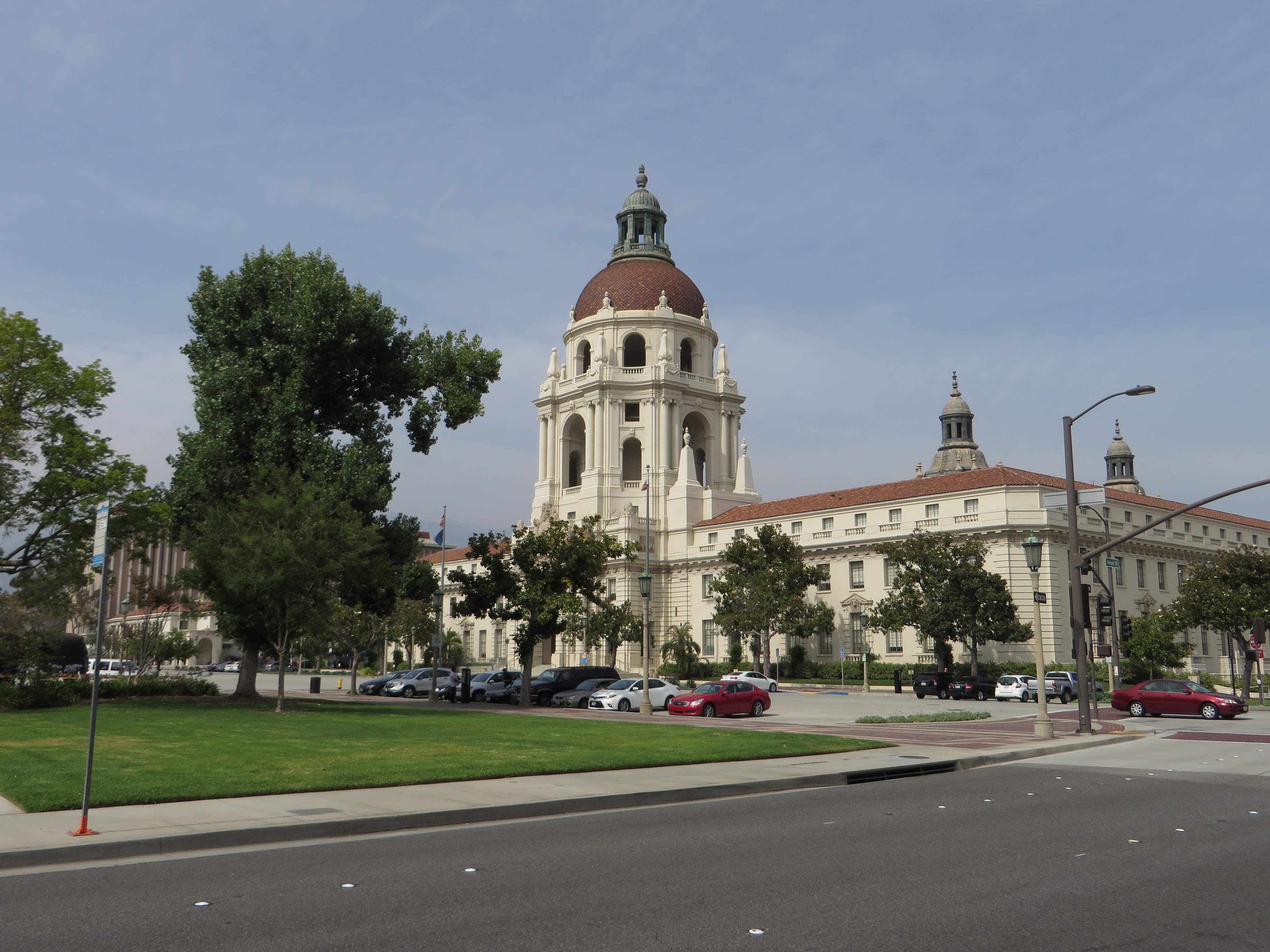 Large domed civic building with cream facade and red tile roof, flanked by trees.