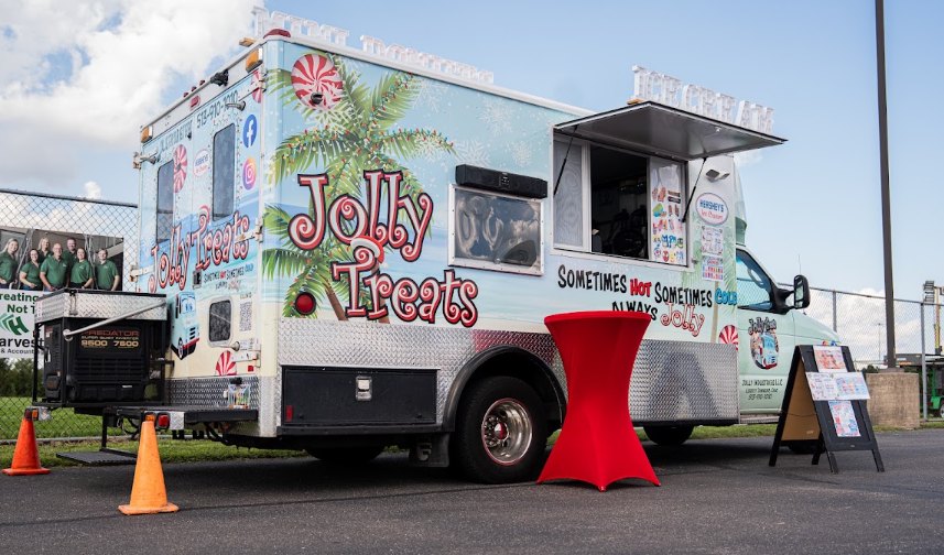 A colorfully wrapped food truck with Christmas and tropical graphics and an open service window.