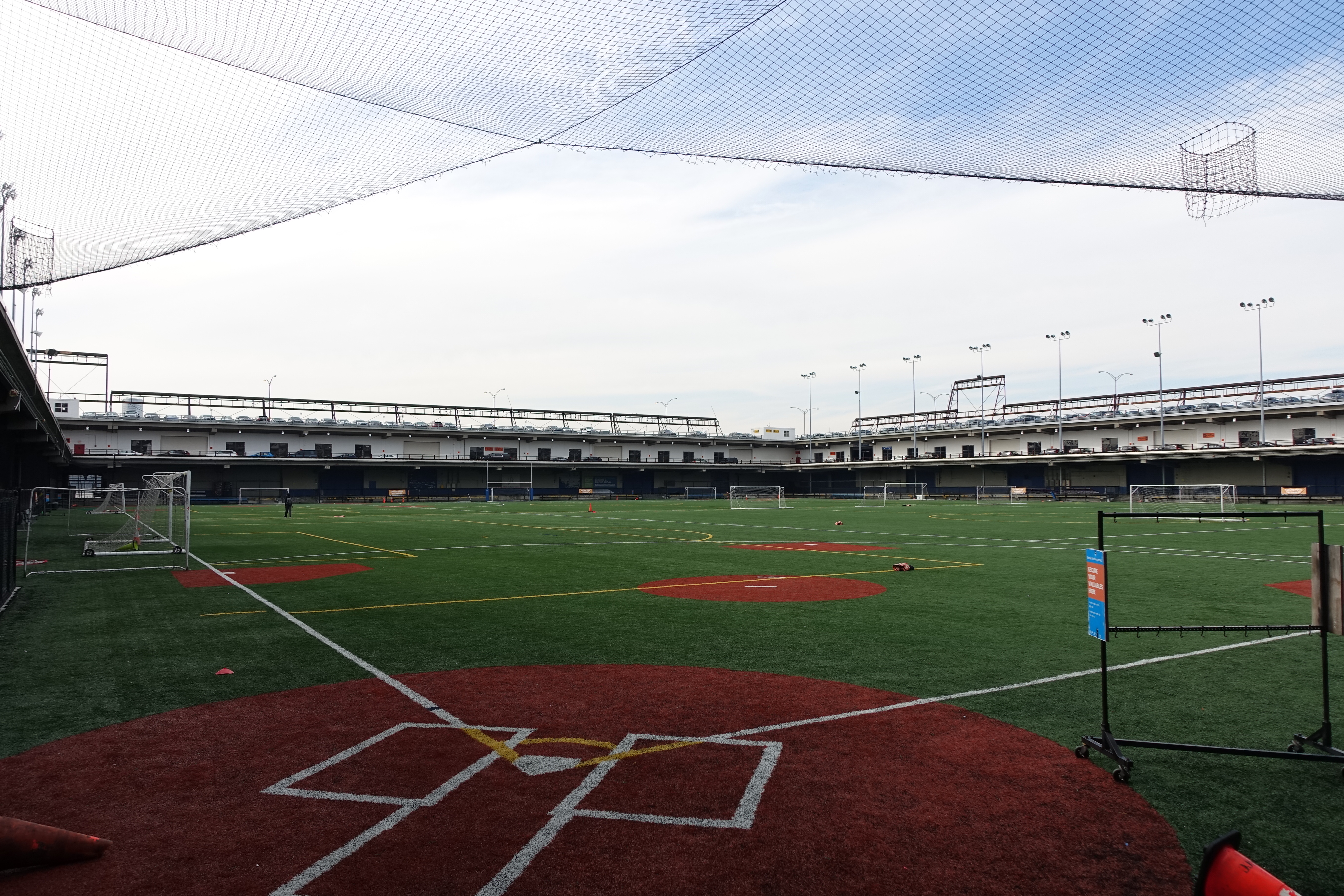 Artificial turf baseball infield with red dirt cutouts and white chalk lines.