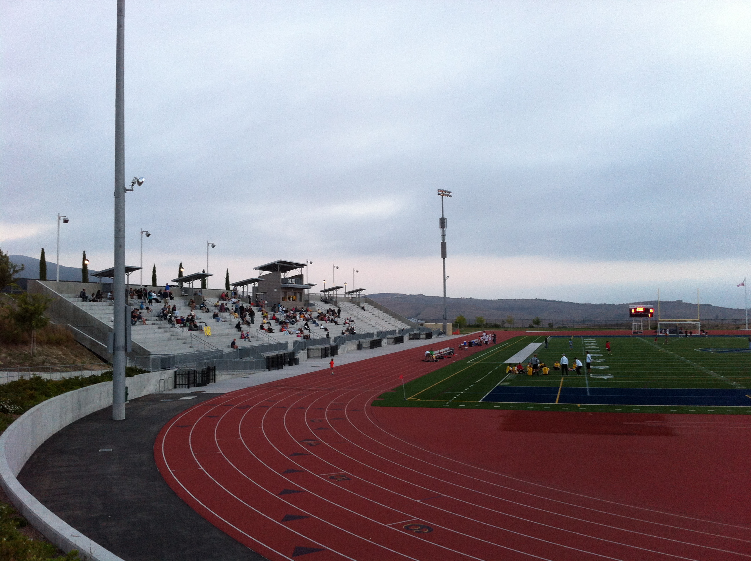 High school stadium with a red running track surrounding a blue artificial turf field.