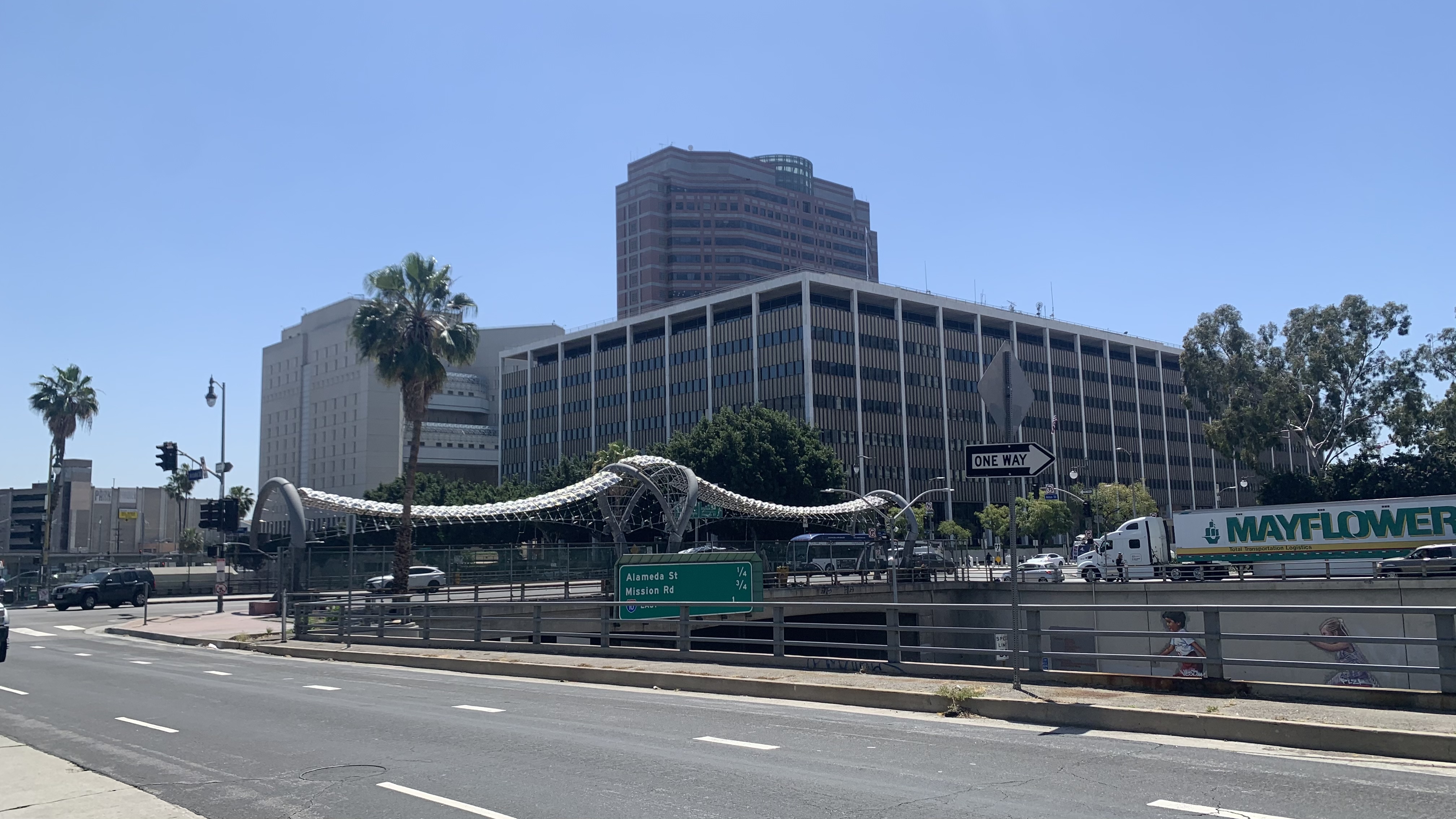 Federal building complex with a white wave-shaped canopy, palm trees, and a highway overpass.